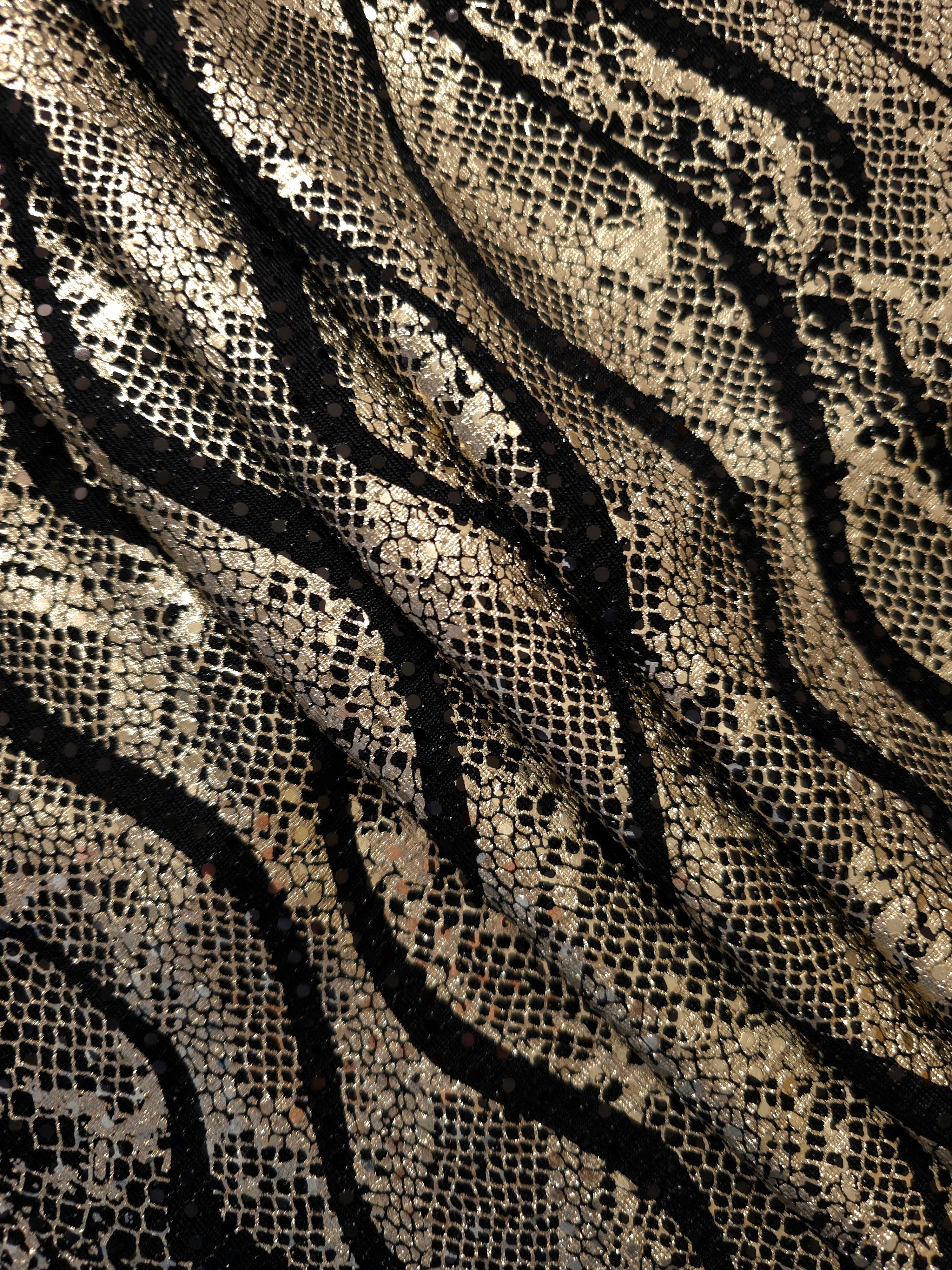 Relaxed folds in Soft Gold Wavy Python sequin tulle reveal reflective metallic patterning over the sheer black base for evening separates, sheer overlays and costume accents.