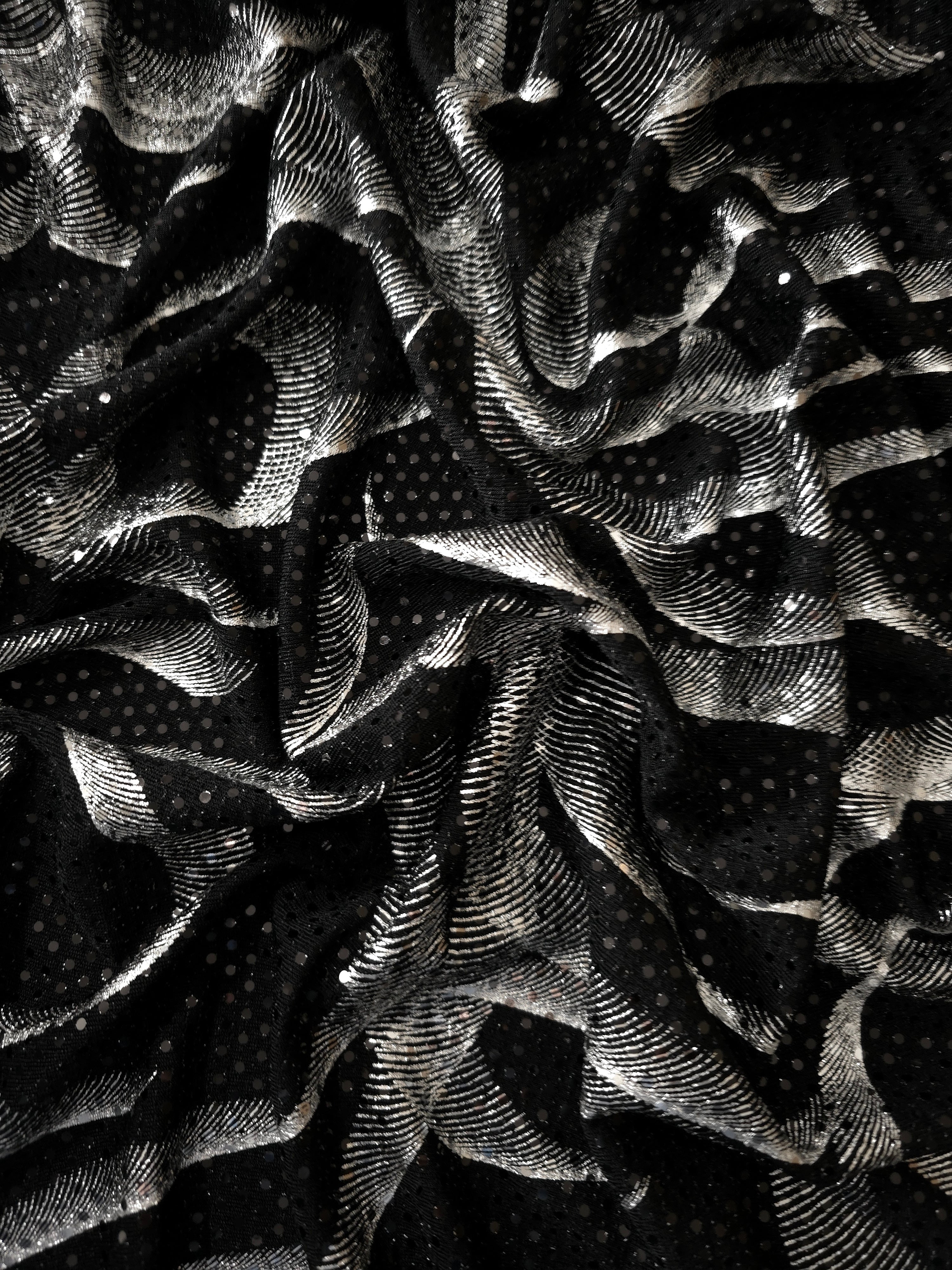 Flowing drape of Silver Gray Abstract Ribbon foil sequin fabric over a black mesh base, highlighting shimmer and fluid fall for prom dresses, cocktail looks and statement overlays.