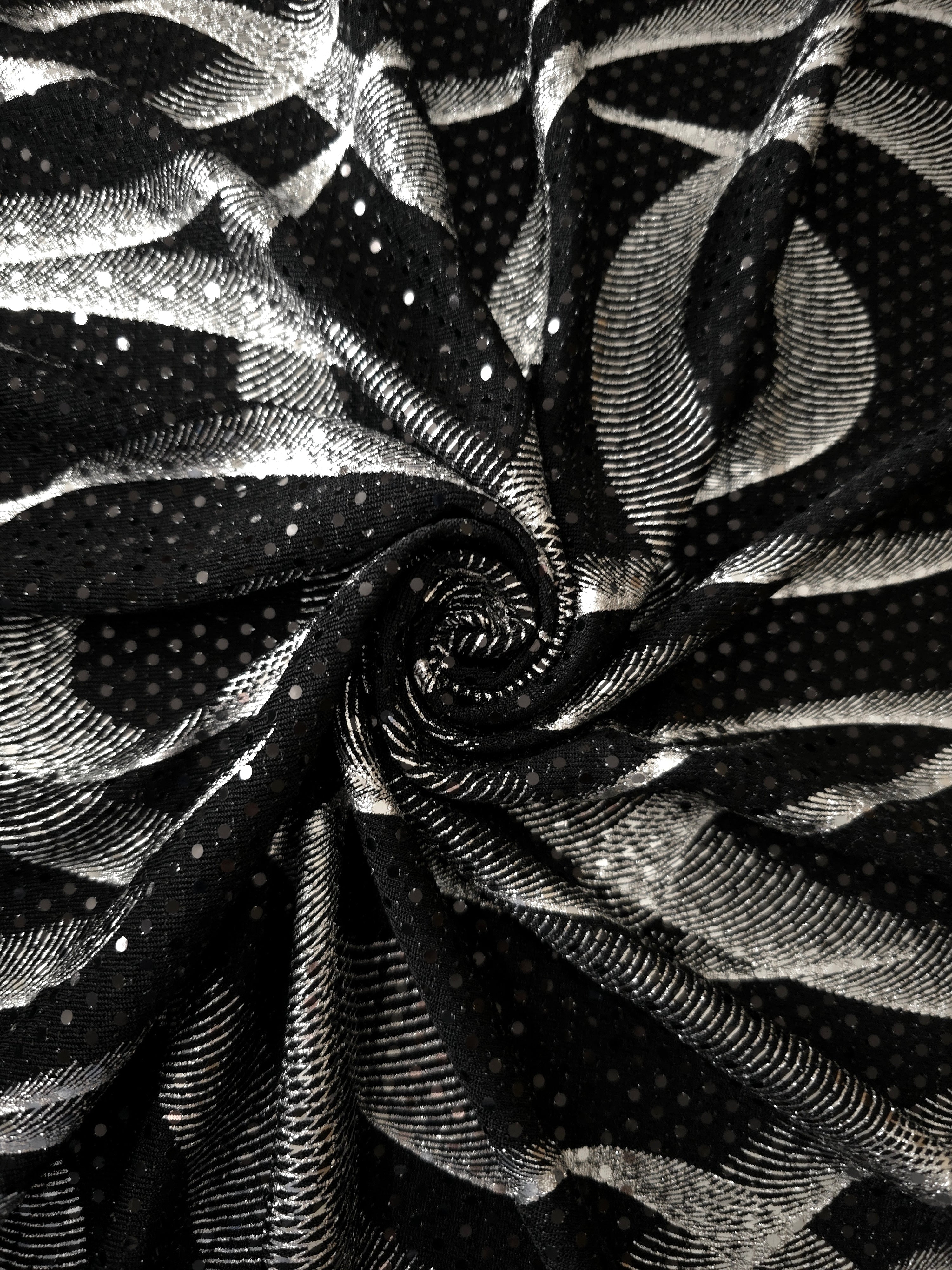Twisted drape of Silver Gray Abstract Ribbon metallic foil sequin fabric, emphasizing light-catching movement over black tulle for formal dresses, cape details and performance costumes.