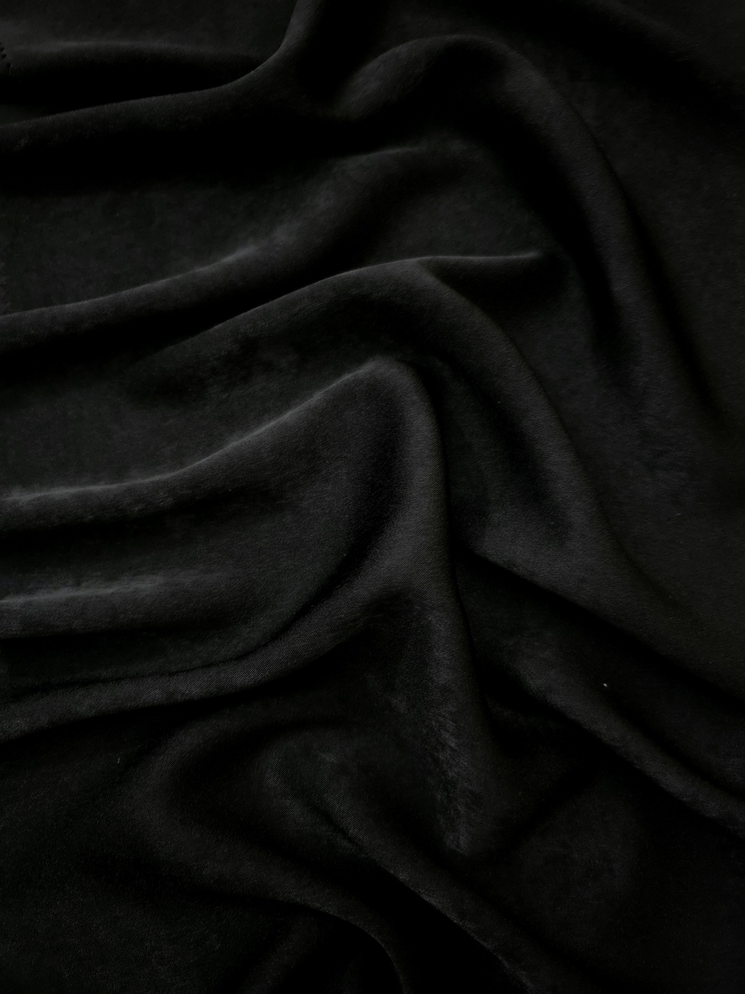 Close-up of Obsidian Black Milano sandwashed silky fabric showing its smooth matte texture and soft surface