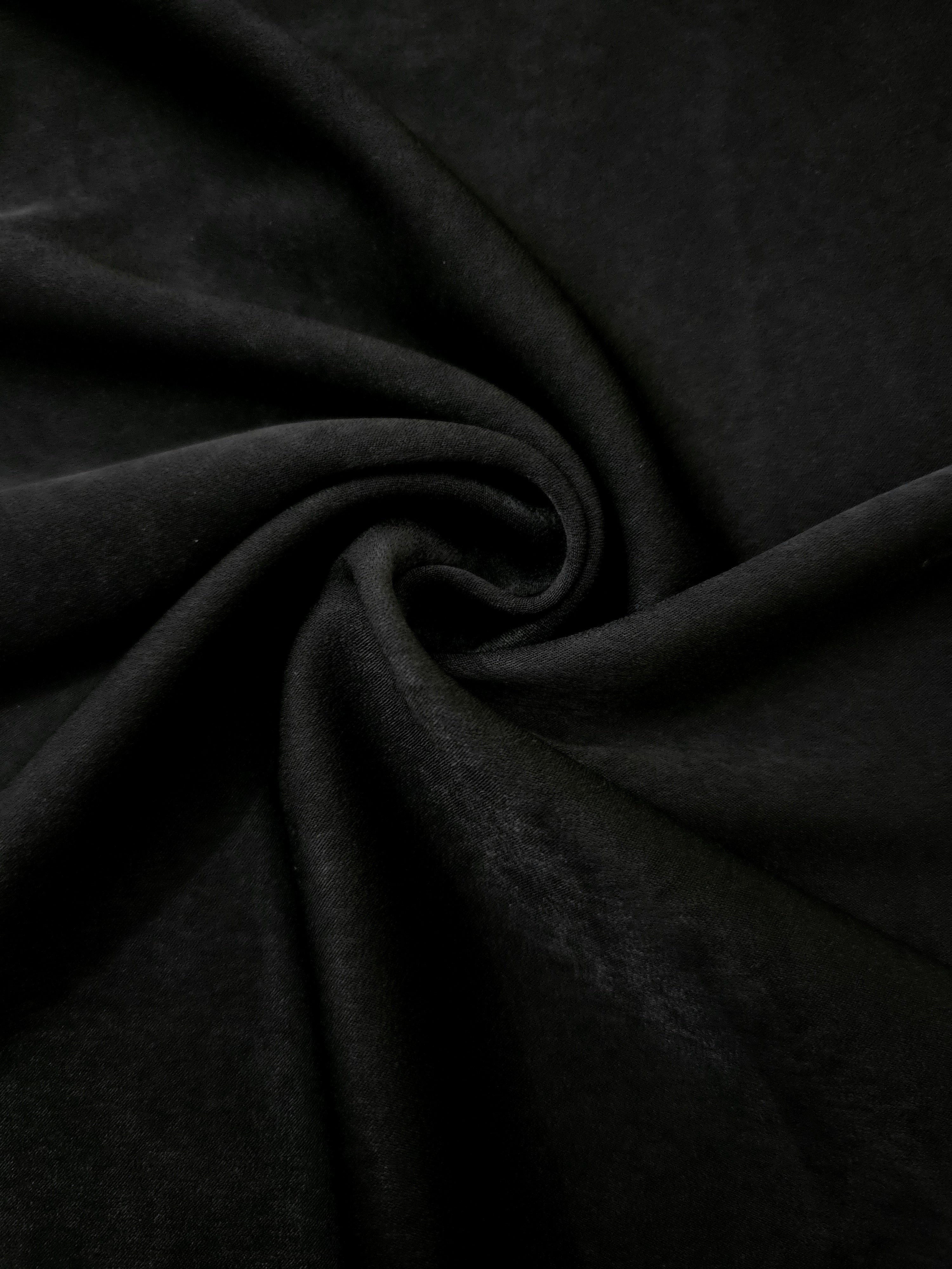 Soft folded detail of Obsidian Black Milano sandwashed silky fabric highlighting its matte finish and supple hand