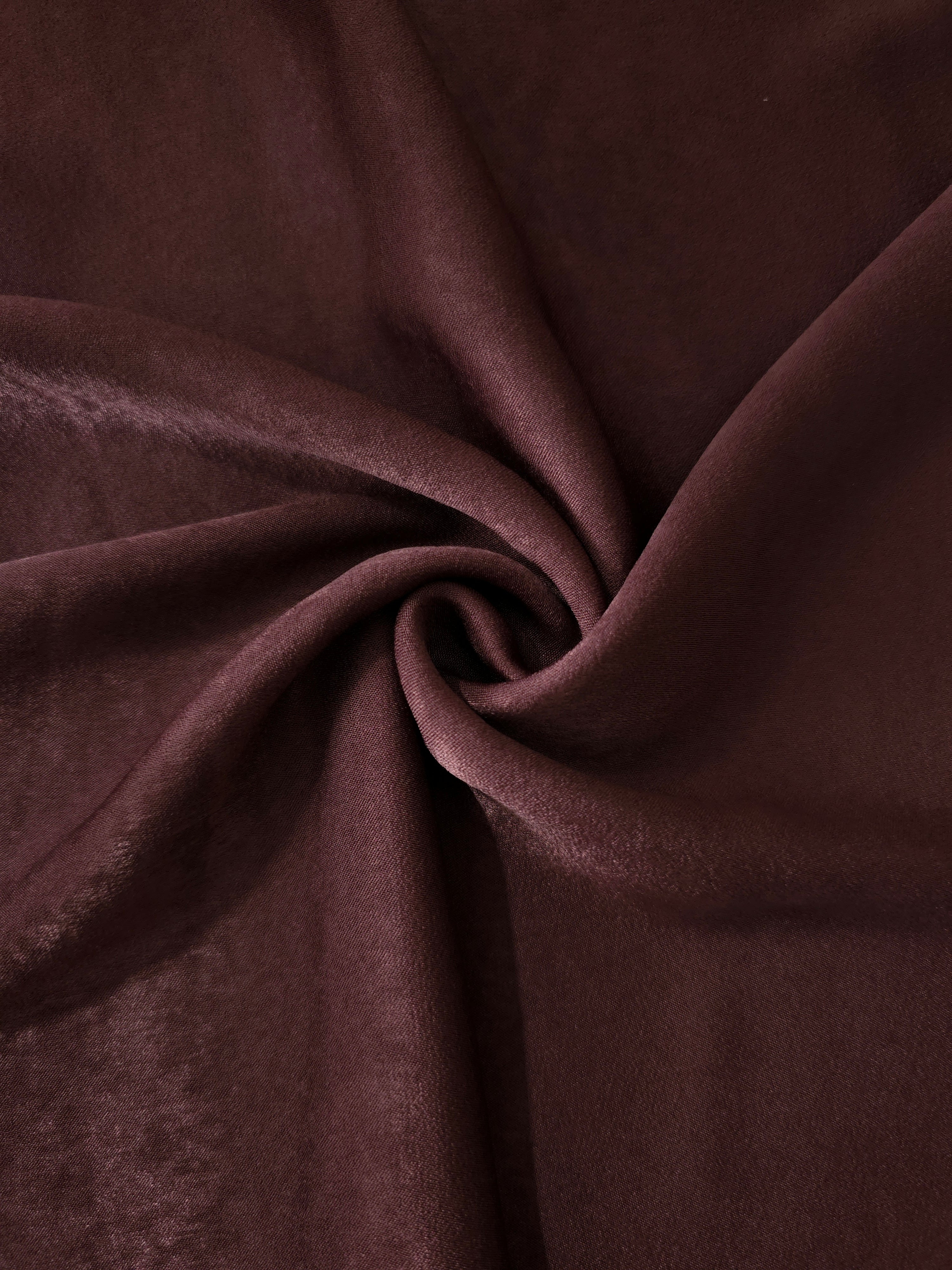 Soft folded detail of Oxblood Mahogany Milano sandwashed silky fabric highlighting its matte finish and supple hand
