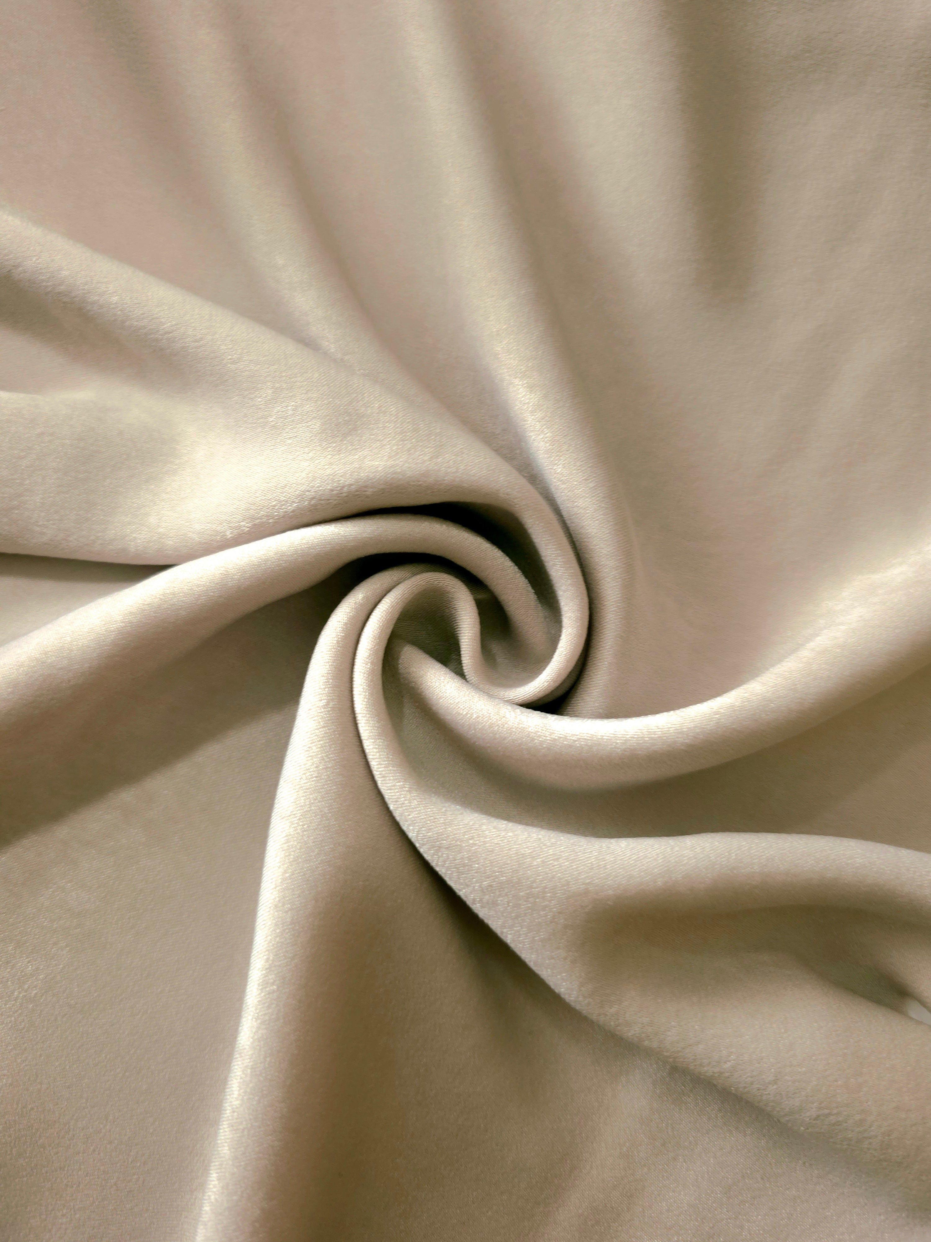 Soft folded detail of Warm Greige Milano sandwashed silky fabric highlighting its matte finish and supple hand
