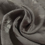 Close drape of tonal flower brick jacquard showing folds and texture.