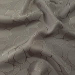 Wave fold of tonal mosaic jacquard showing satin-on-matte woven contrast.
