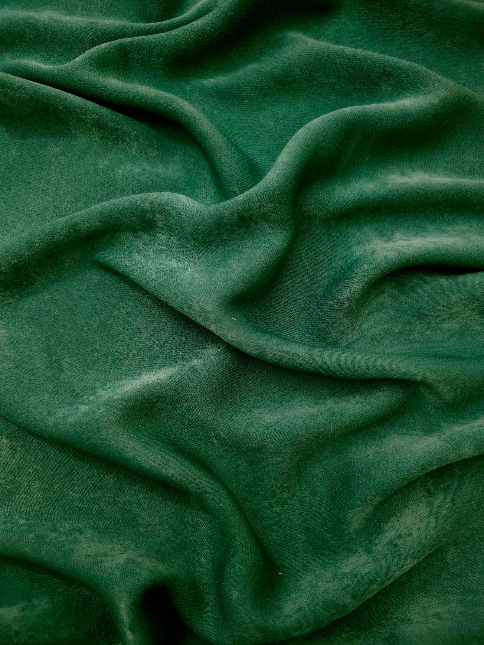Close-up texture of Emerald Green sandwashed silky polyamide fabric