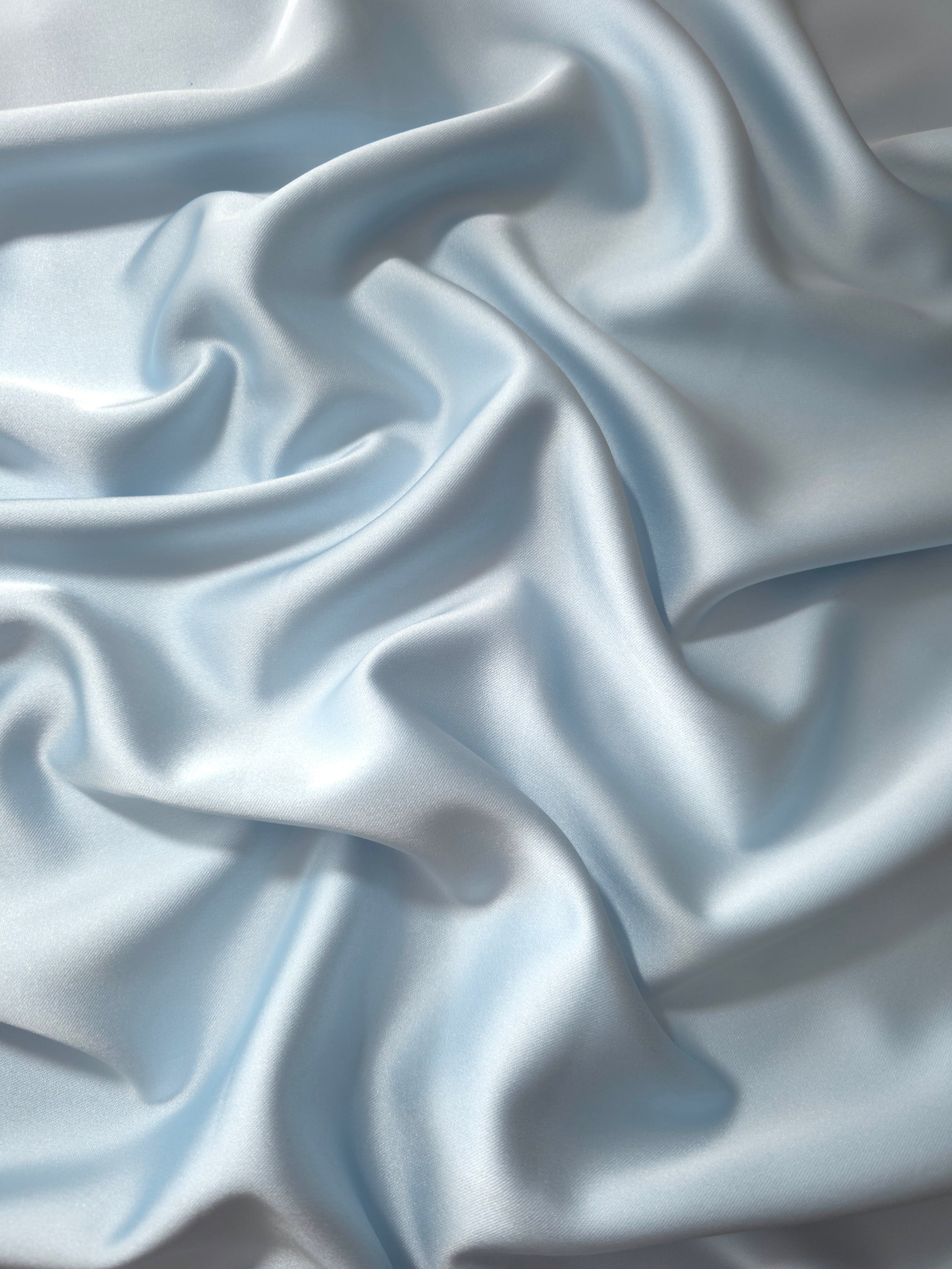 Draped Baby Blue silky satin fabric showing a smooth luminous surface and fluid fall for bridesmaid dresses, soft evening gowns and romantic occasionwear.