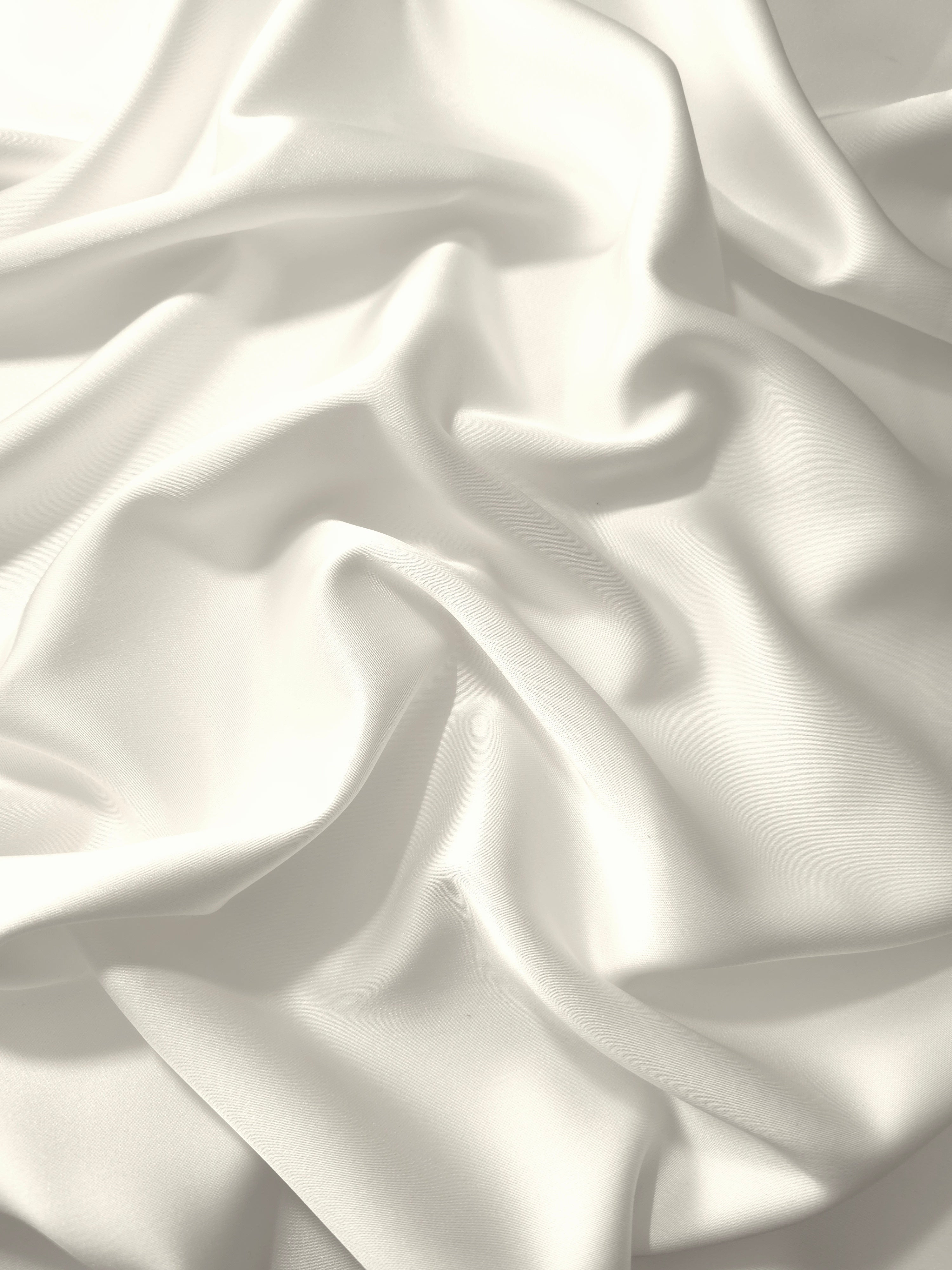 Cloud White silky satin in a full drape, displaying clean luminosity and smooth movement for bridal gowns, reception dresses and ceremonial fashion.