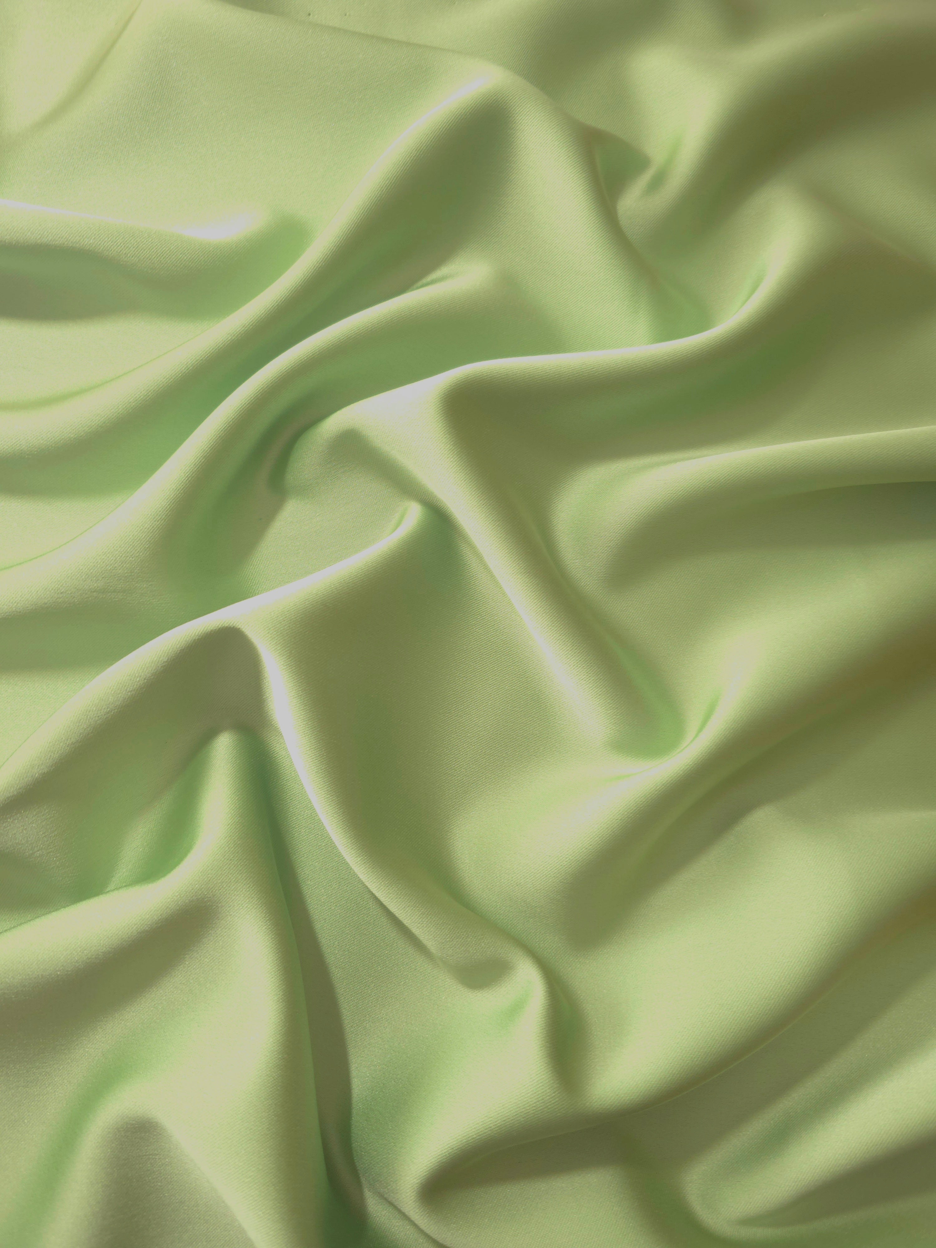 Mint Green silky satin shown in a fresh flowing drape, reflecting light softly for bridesmaid dresses, spring gowns and elegant garden-party looks.
