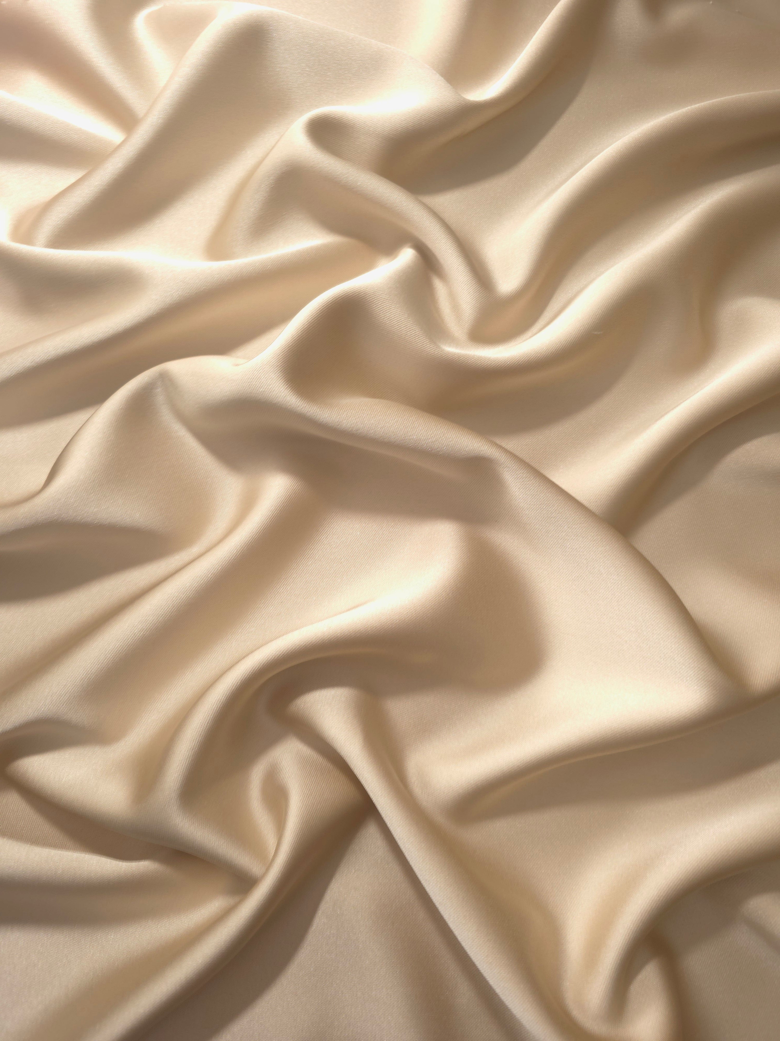Warm Nude silky satin shown in a flowing drape, with soft shine and elegant movement for minimalist gowns, bridesmaid dresses and neutral evening looks.