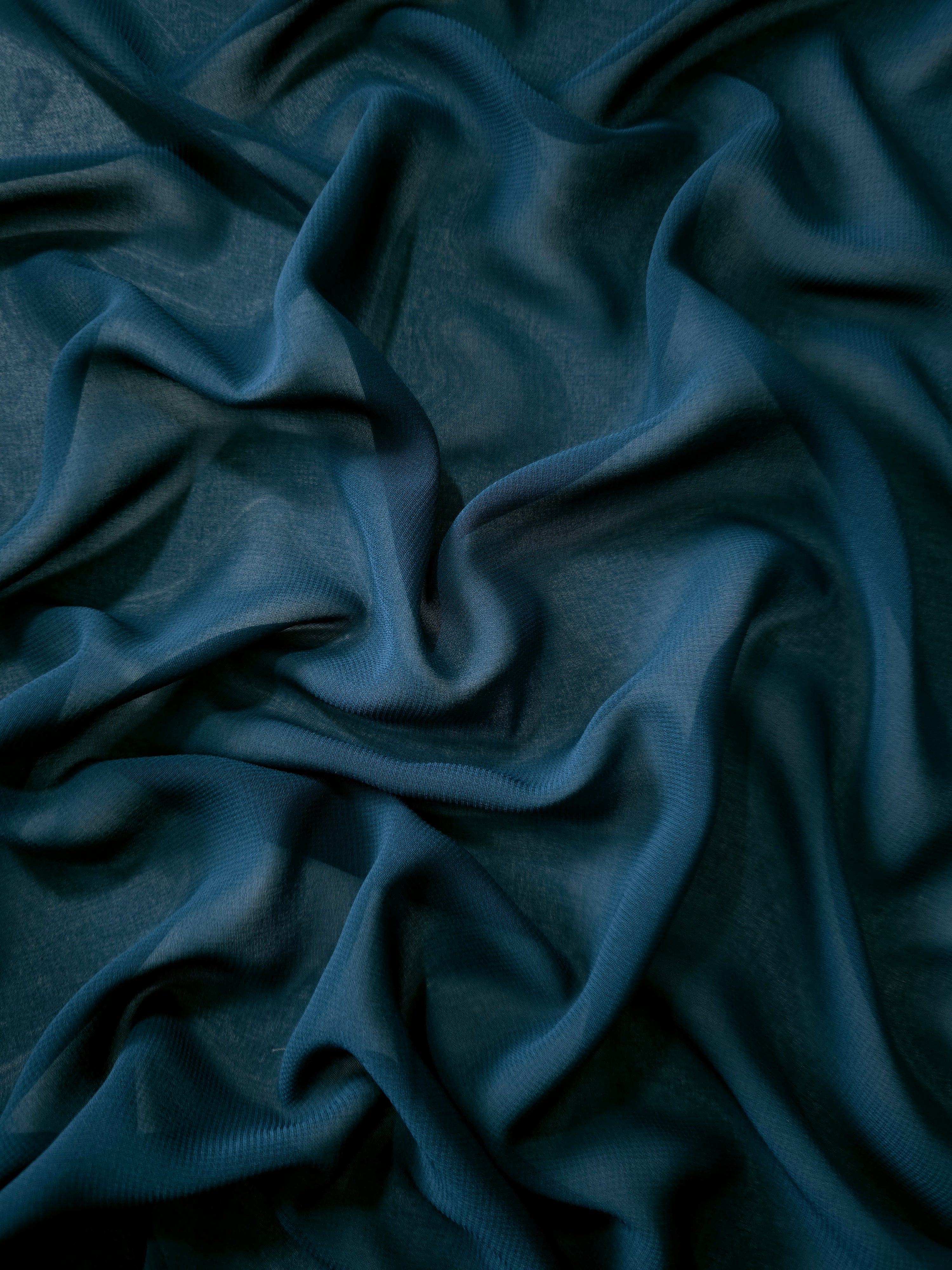 Deep Petrol Teal stretch chiffon arranged in long draped folds to show movement for evening gowns, flowing skirts and layered occasionwear.