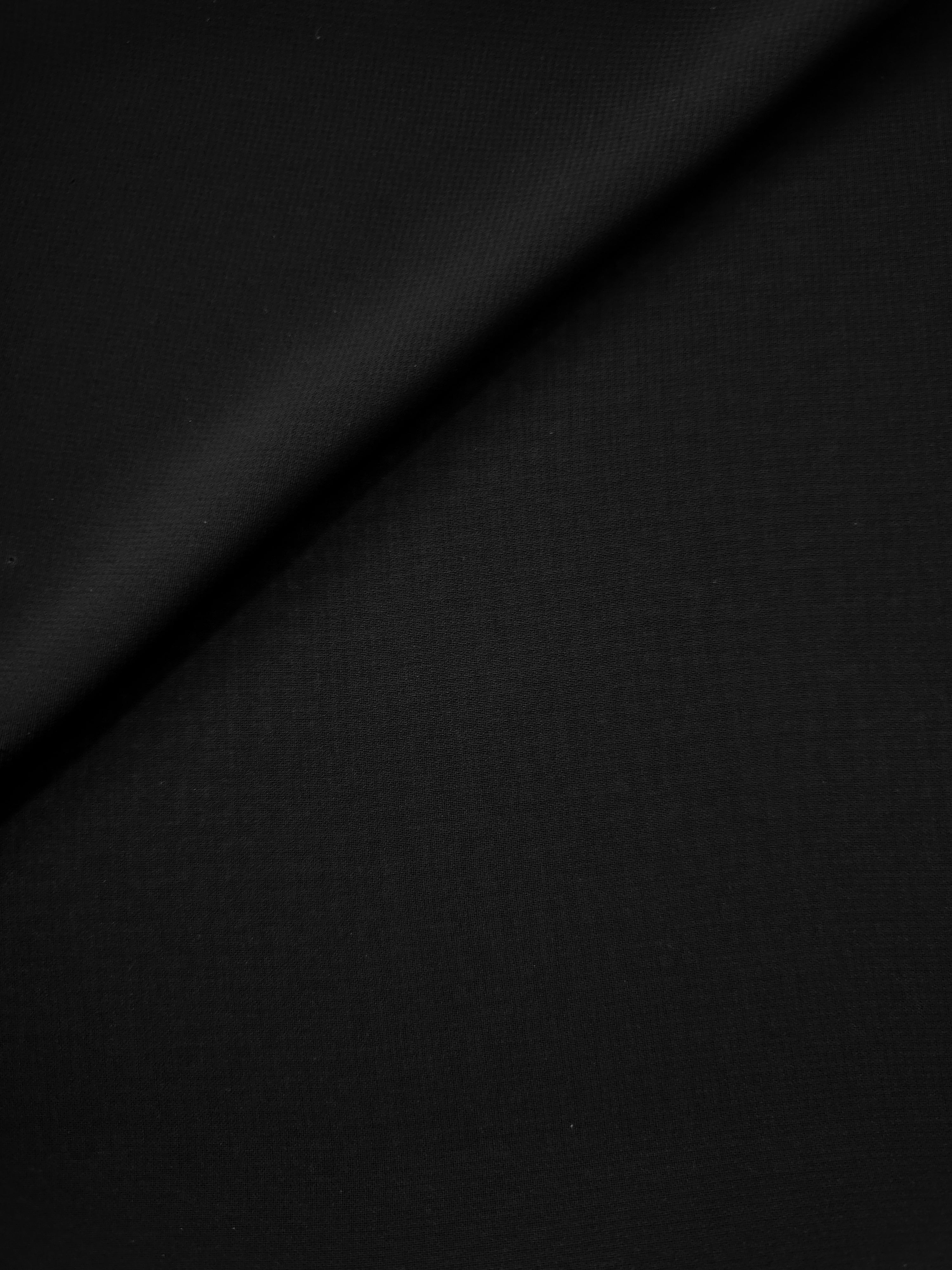 Full surface of Jet Black silky chiffon stretch fabric, presenting a light flowing base for evening tops, sheer skirt overlays and statement dresses.