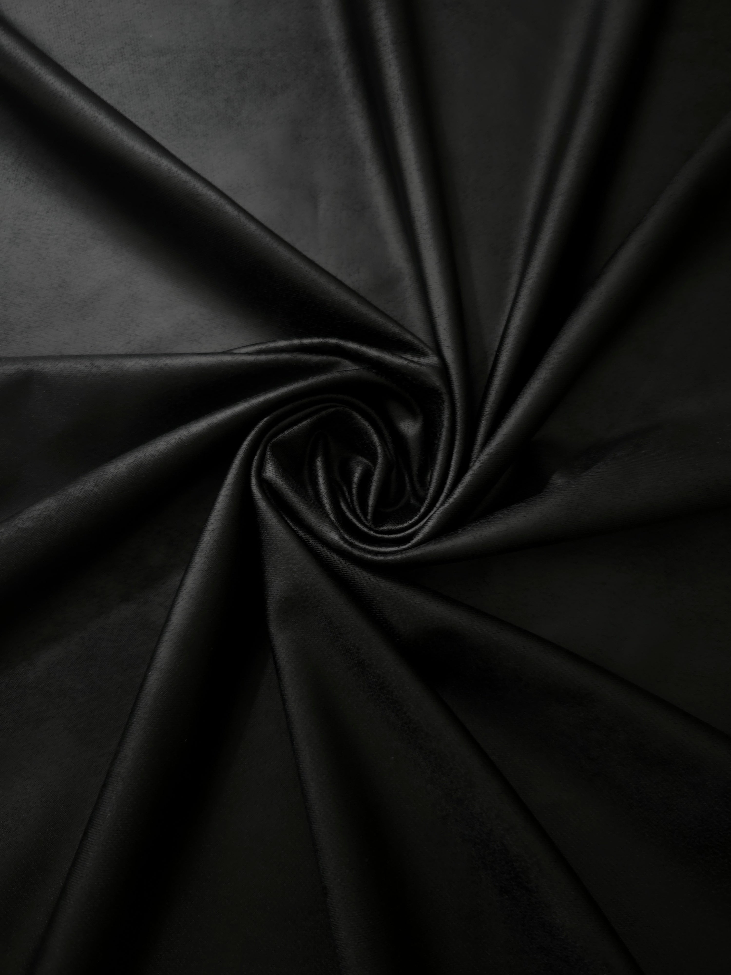 Spiral arrangement of black leather-effect stretch fabric emphasizing supple folds for performance wear, costumes and statement tops.
