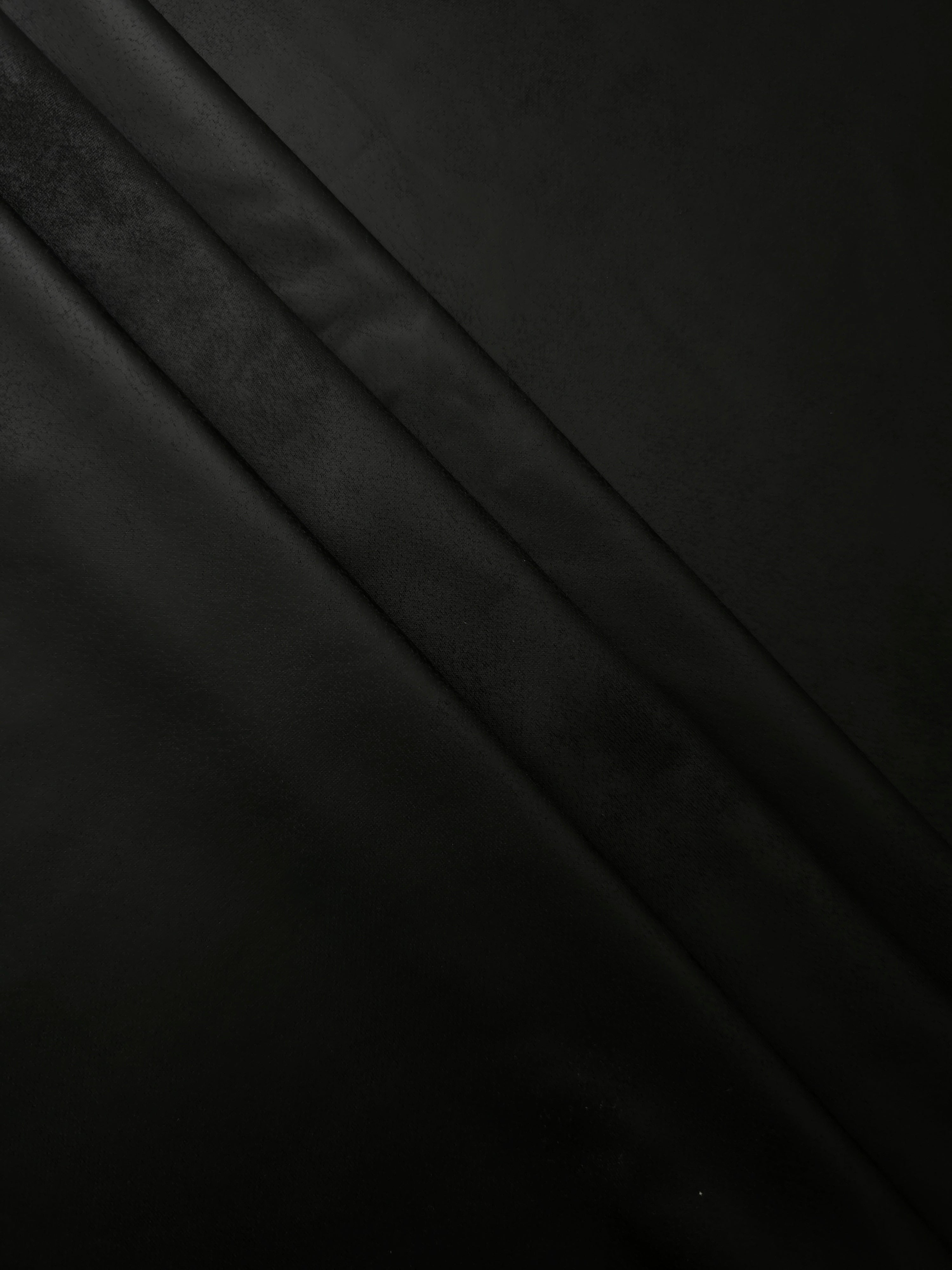 Layered black stretch faux leather folds show soft structure and recovery for fitted skirts, pants and contemporary fashion separates.
