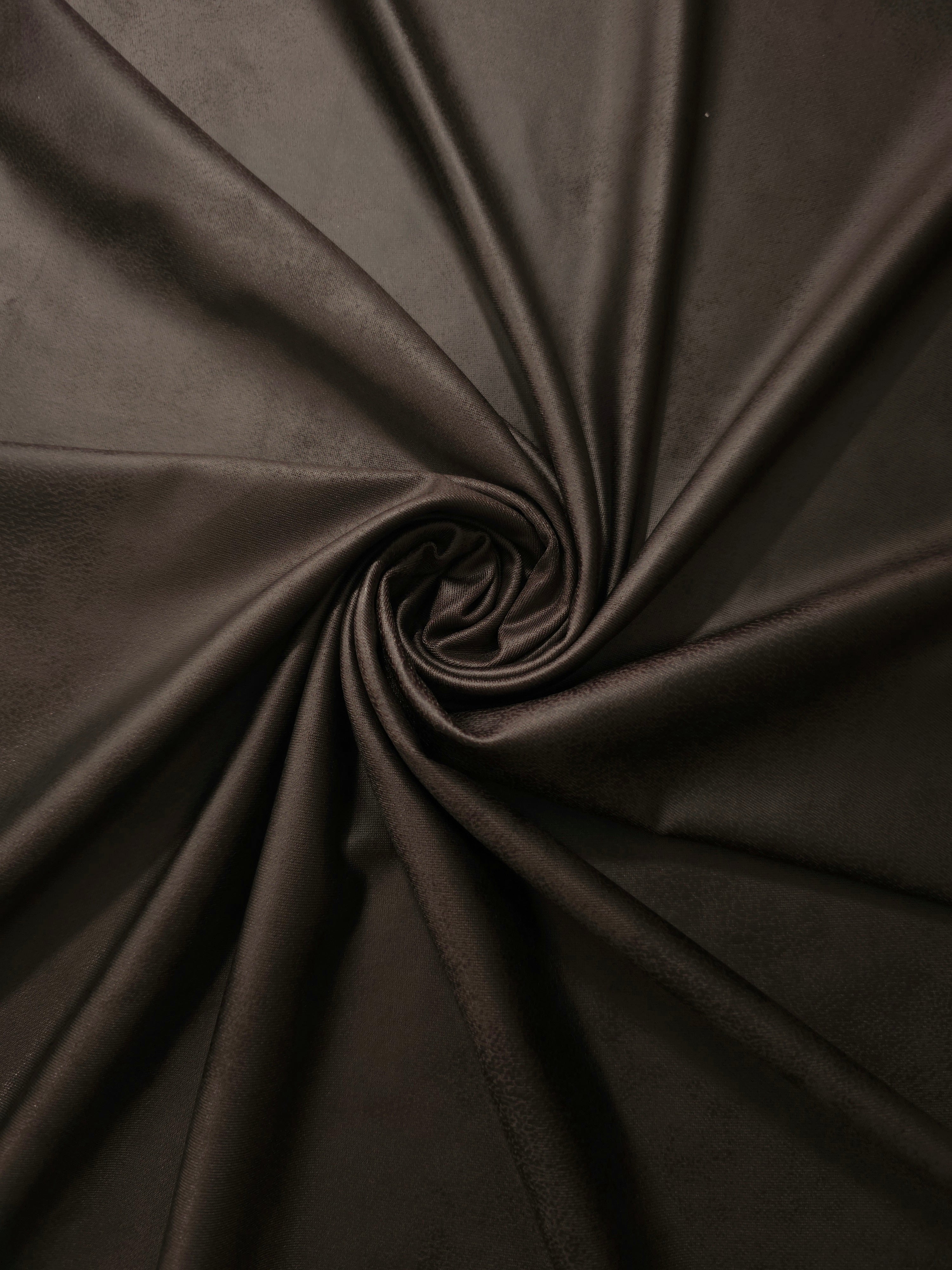 Spiral-folded deep espresso brown faux leather stretch fabric highlighting supple structure for fashion tops, dresses and statement sleeves.