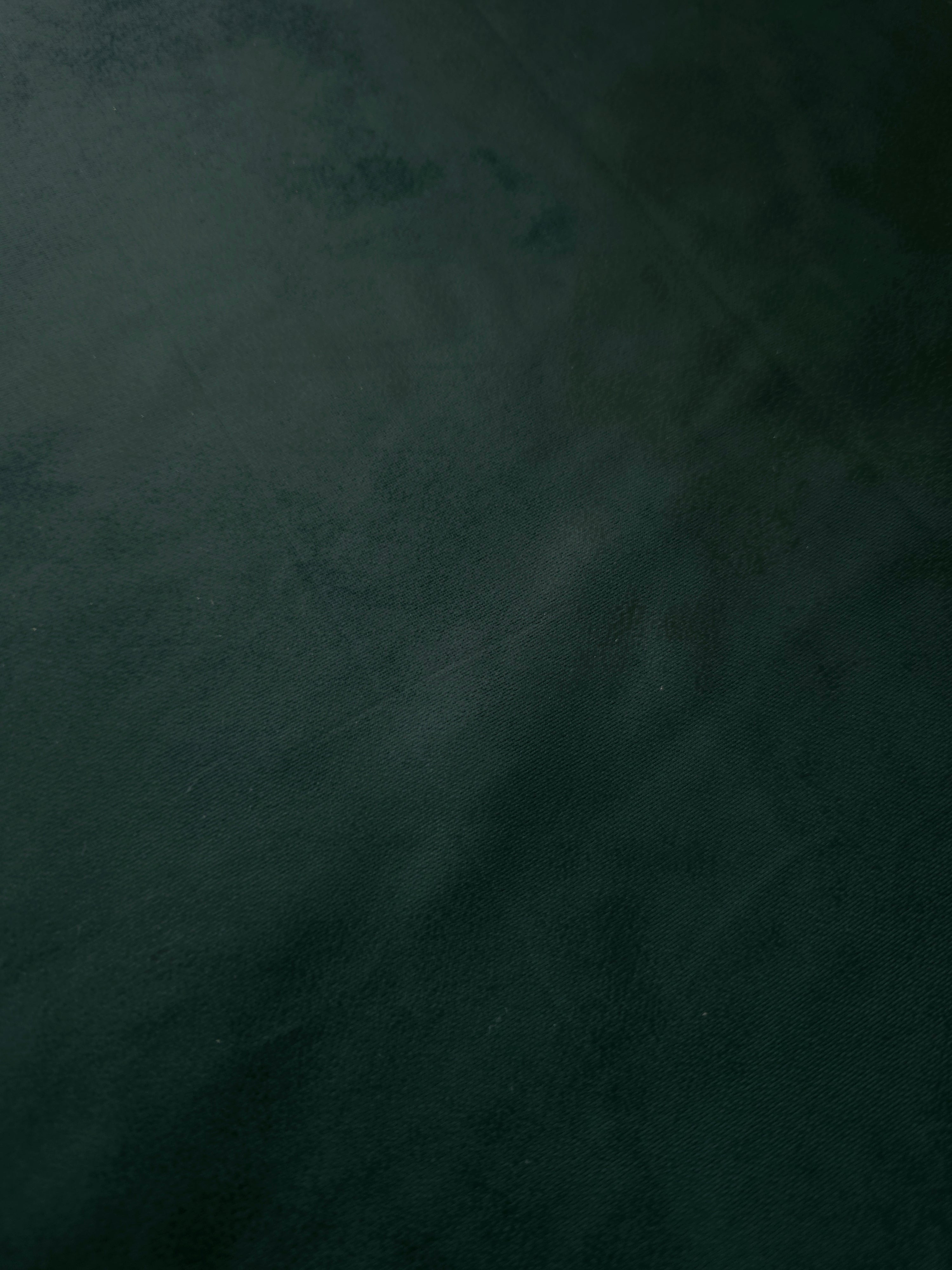 Deep forest green stretch faux leather laid flat, highlighting a smooth flexible surface for dresses, trousers and tailored panels.