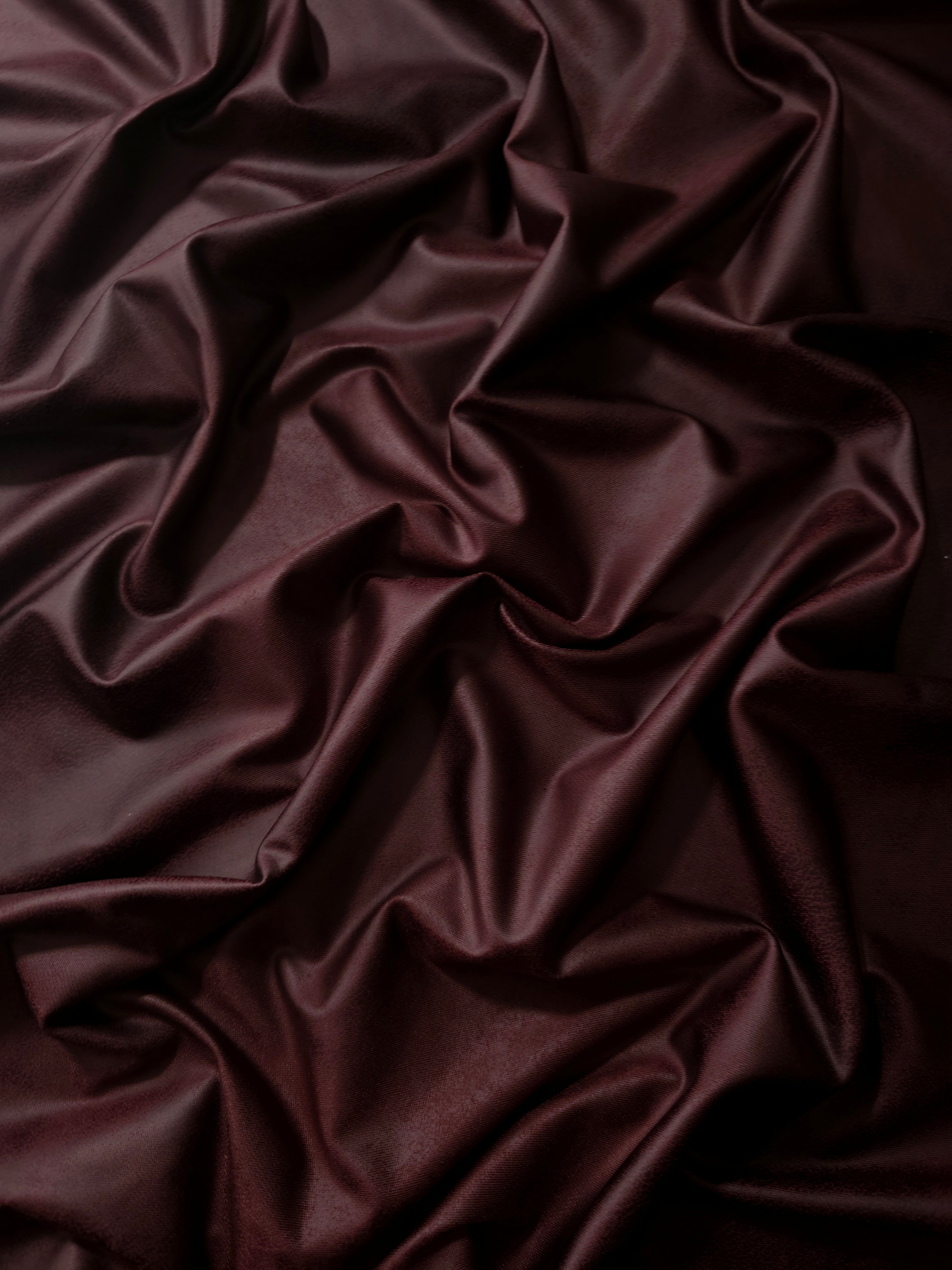 Relaxed drape of deep plum soft faux leather stretch fabric showing flexibility for wrap skirts, fitted dresses and fashion panels.