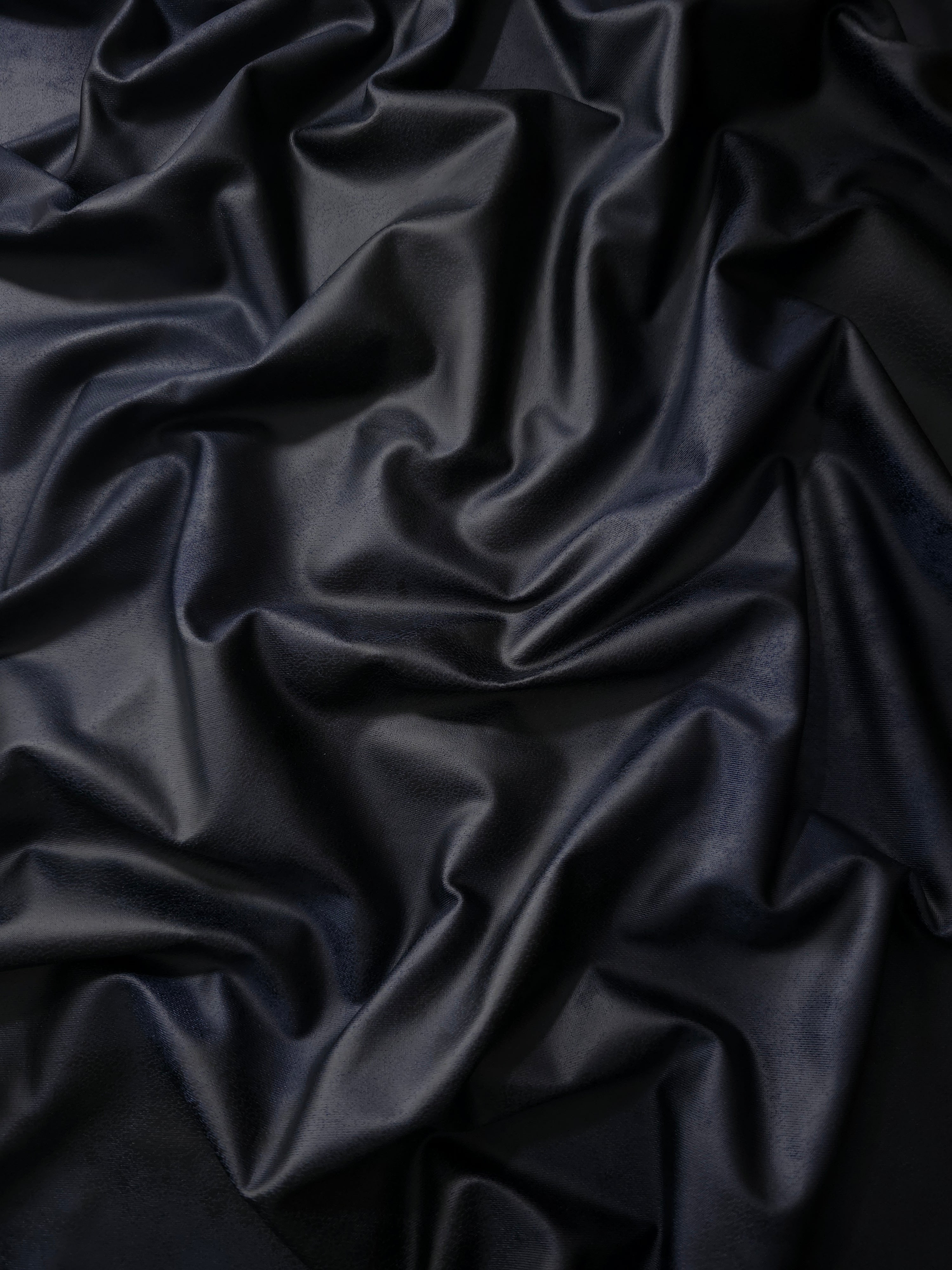 Relaxed folds of midnight navy soft faux leather stretch fabric demonstrate flexibility for fitted dresses and pencil skirts.