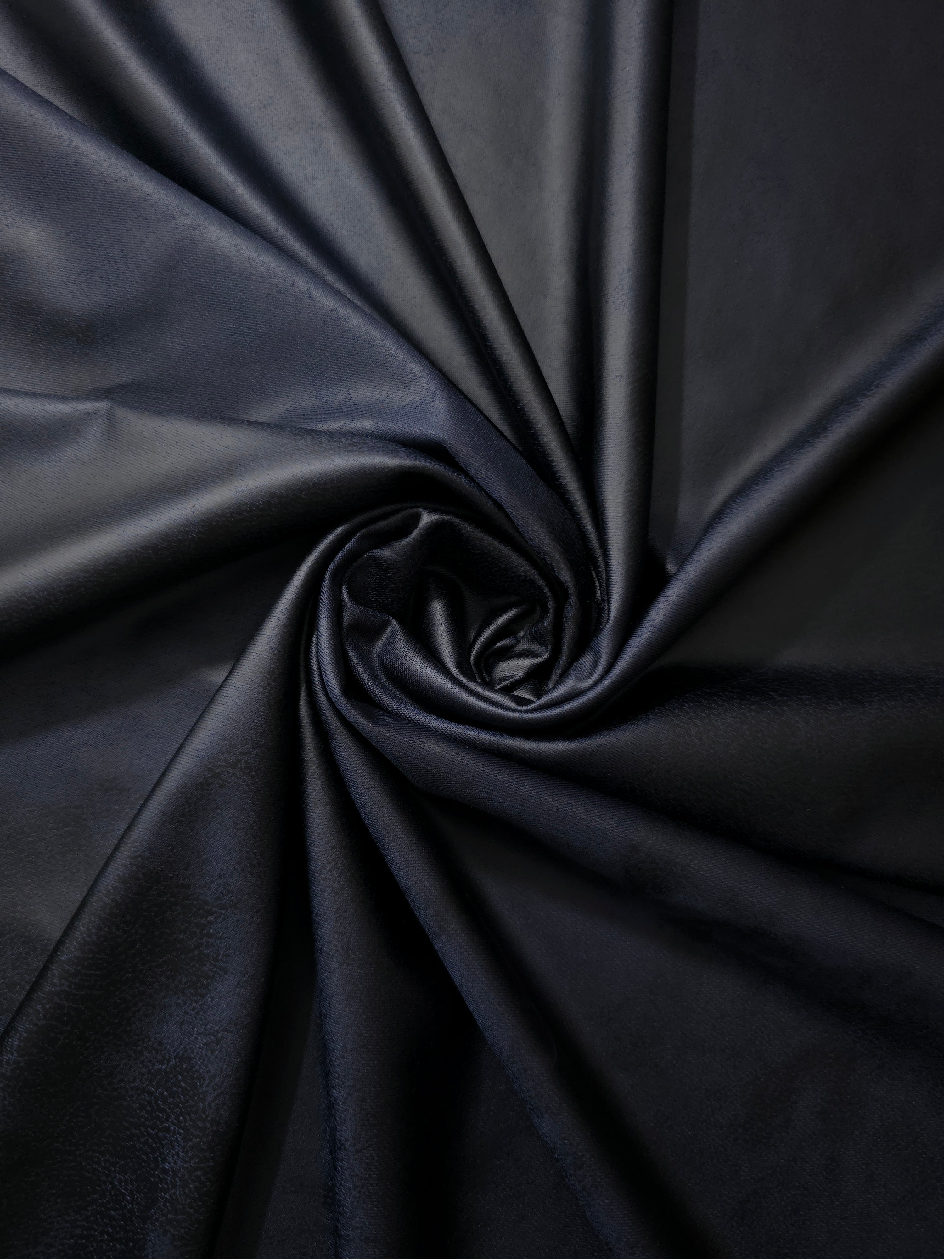 Spiral-folded midnight navy leather-effect stretch fabric shows supple shaping for statement tops, eveningwear and costume design.
