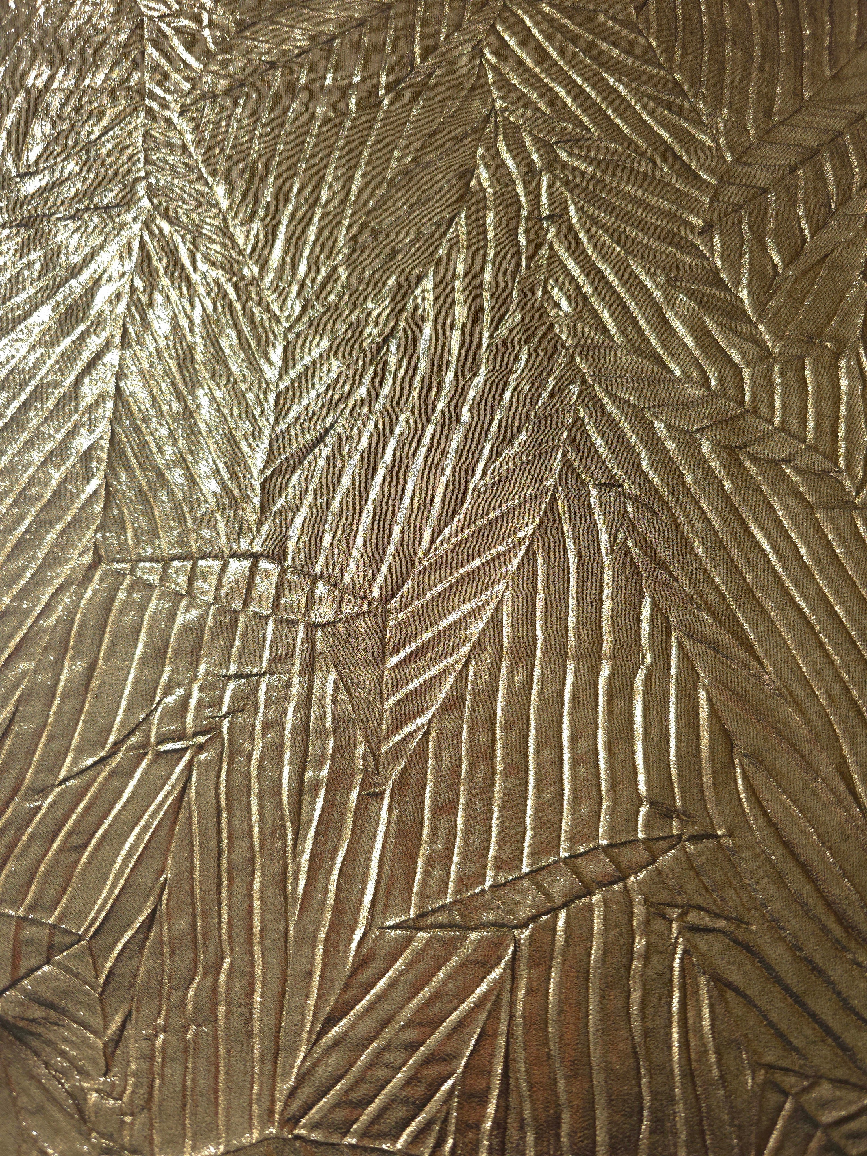 Surface detail of Antique Gold leaf-pattern plissé shimmer fabric showcases sculpted leaf-like pleats for evening clutches, garment accents and special-occasion pieces.