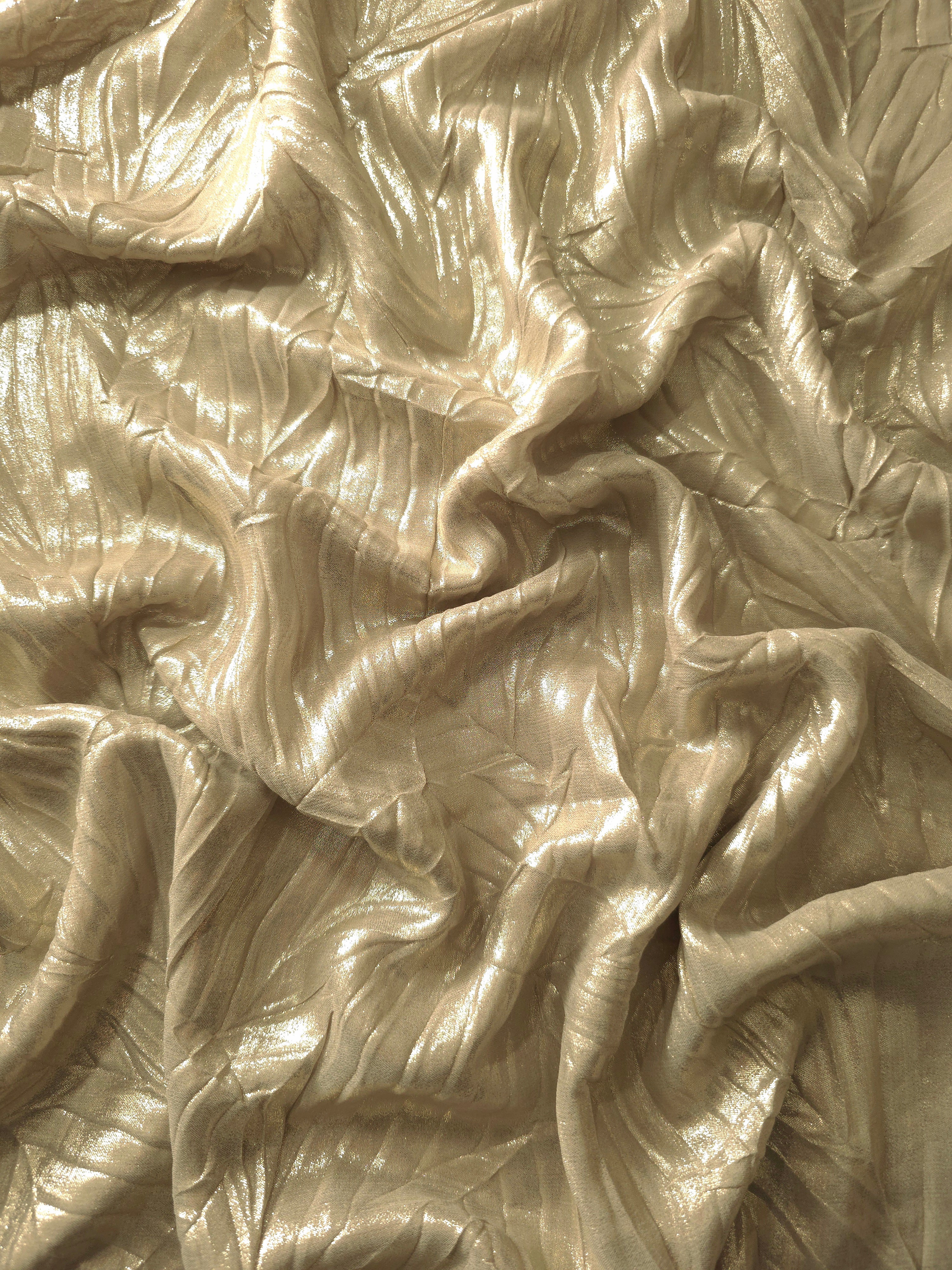 Flowing drape of Champagne Beige leaf-pattern plissé shimmer fabric, showing sculpted leaf-like pleats and light-catching movement for evening gowns and flowing maxi skirts.