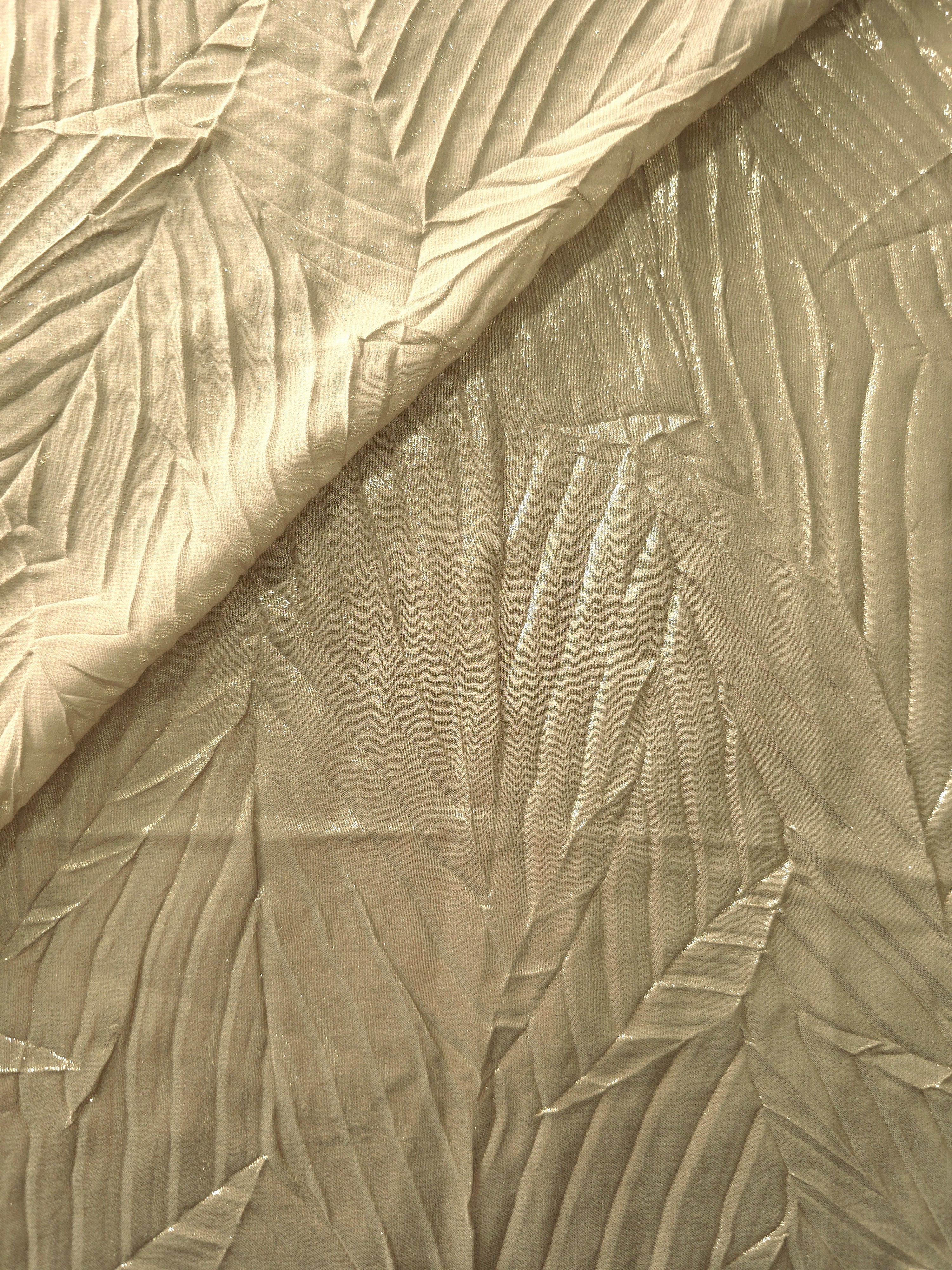Fold detail of Champagne Beige leaf-pattern plissé fabric demonstrates how the textured surface builds depth for stagewear and layered fashion details.