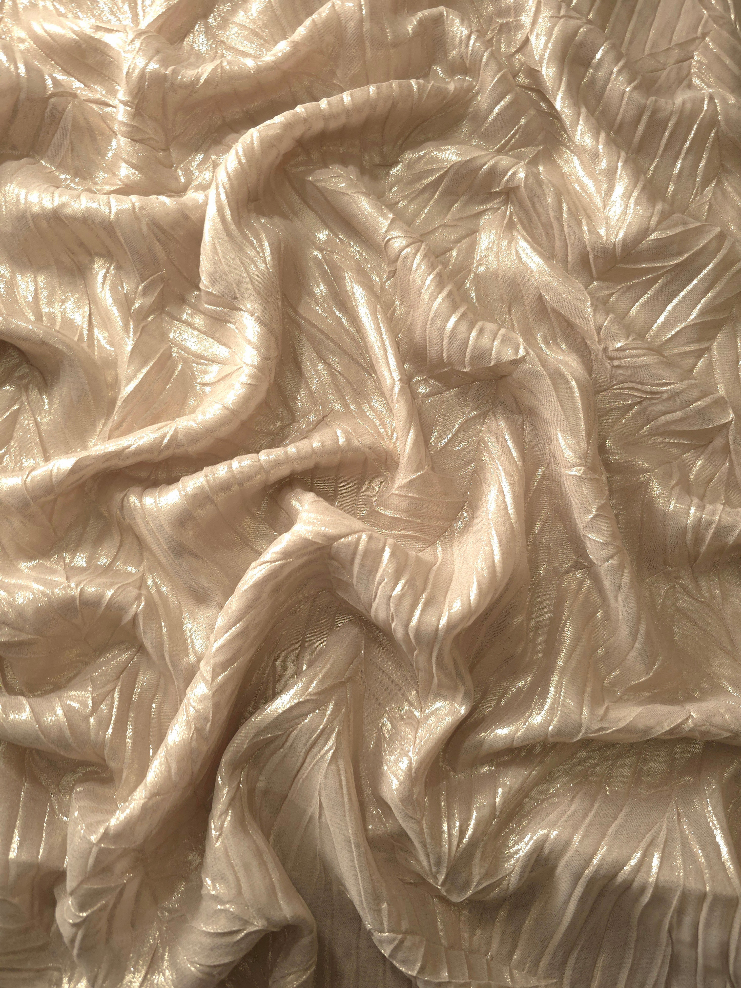 Flowing drape of Champagne Cream leaf-pattern plissé shimmer fabric, showing sculpted leaf-like pleats and light-catching movement for evening gowns and flowing maxi skirts.