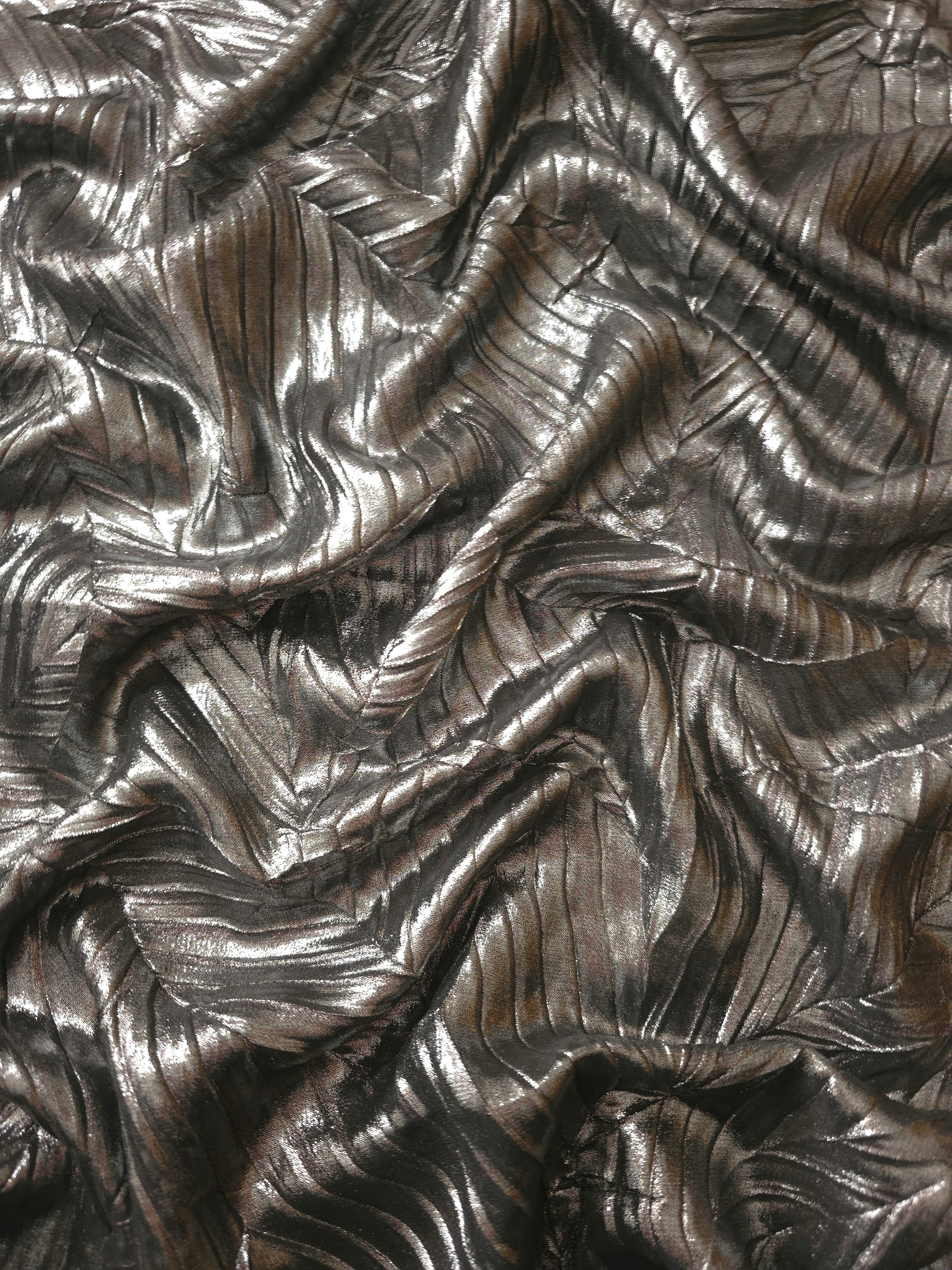 Flowing drape of Graphite Gray leaf-pattern plissé shimmer fabric, showing sculpted leaf-like pleats and light-catching movement for evening gowns and flowing maxi skirts.