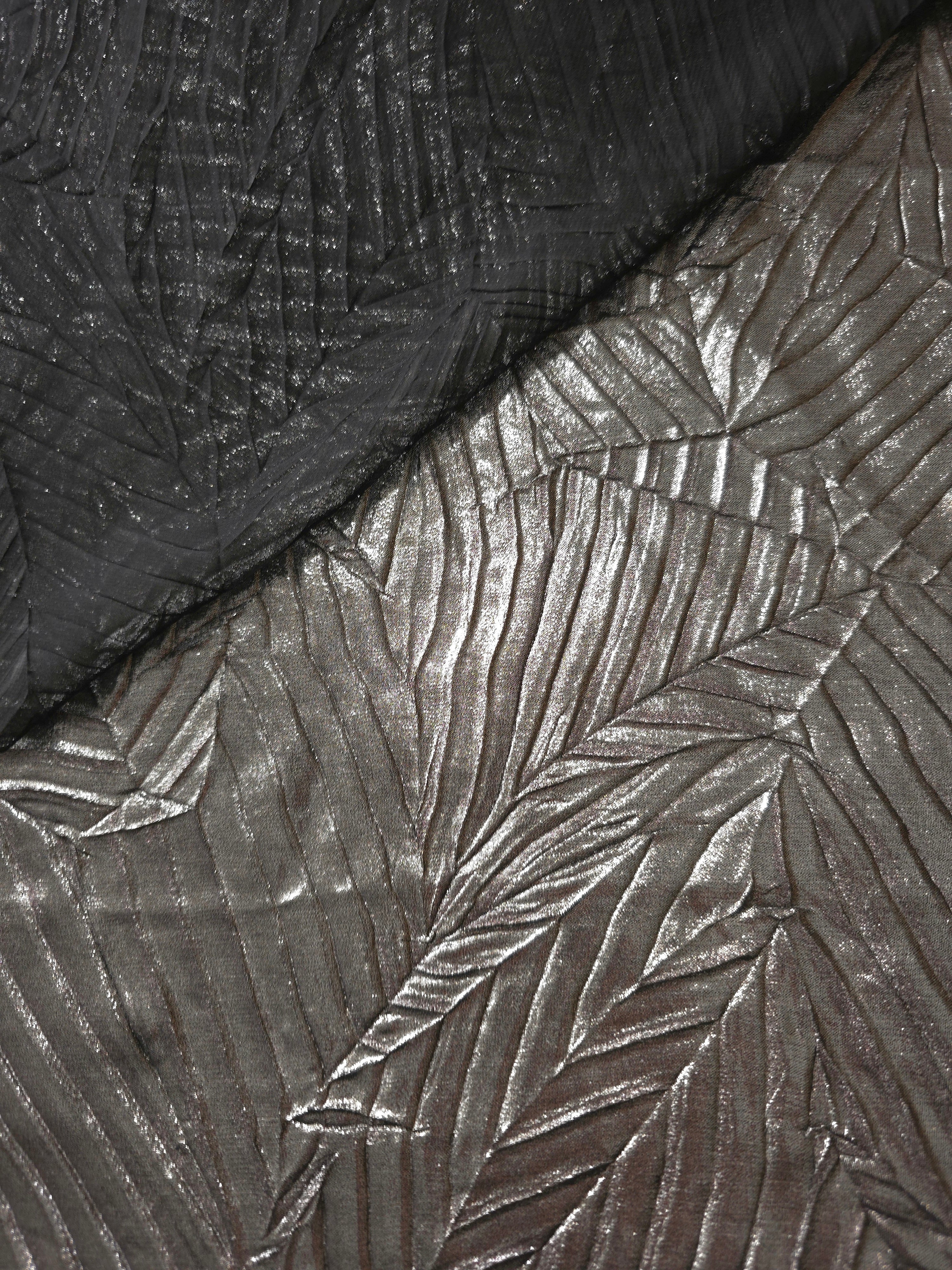 Fold detail of Graphite Gray leaf-pattern plissé fabric demonstrates how the textured surface builds depth for stagewear and layered fashion details.