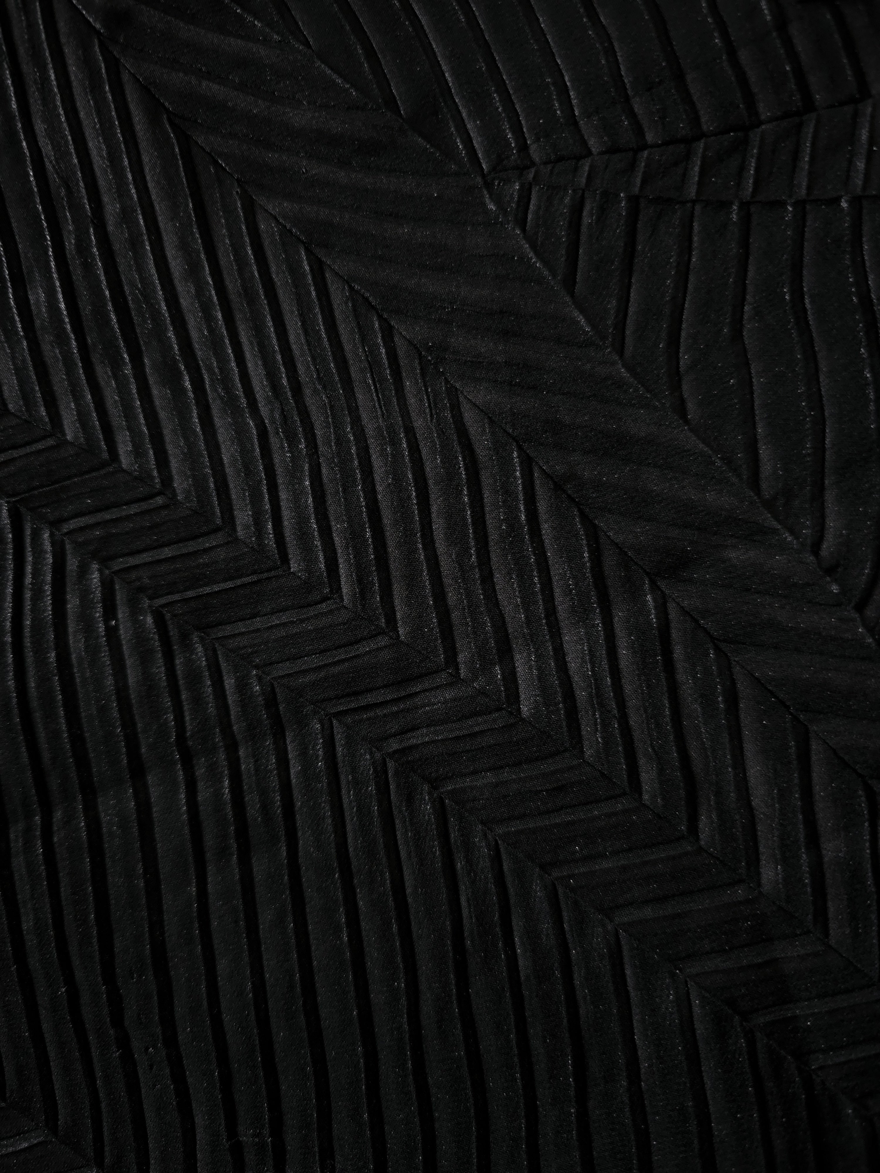 Soft drape of Obsidian Black textured shimmer plissé reveals dimensional folds and shifting reflection for jumpsuits and fluid occasionwear.