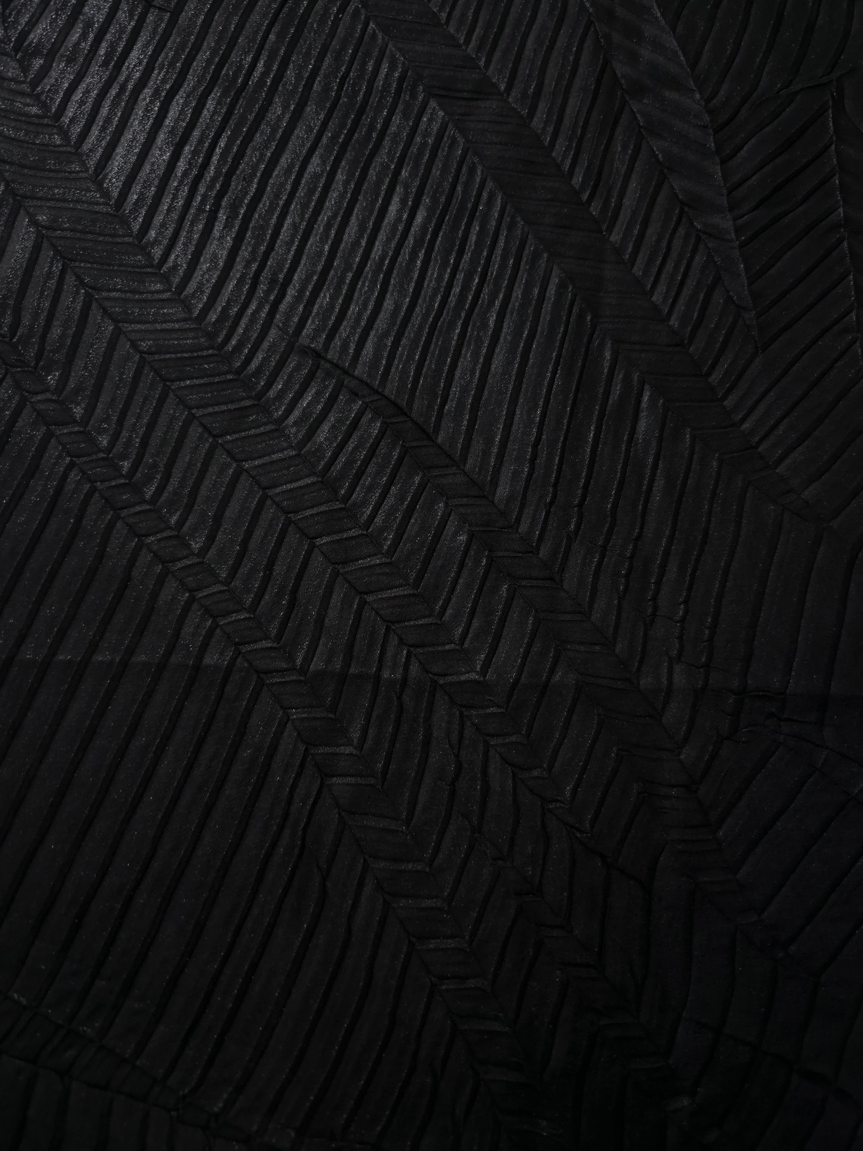 Surface detail of Obsidian Black leaf-pattern plissé shimmer fabric showcases sculpted leaf-like pleats for evening clutches, garment accents and special-occasion pieces.