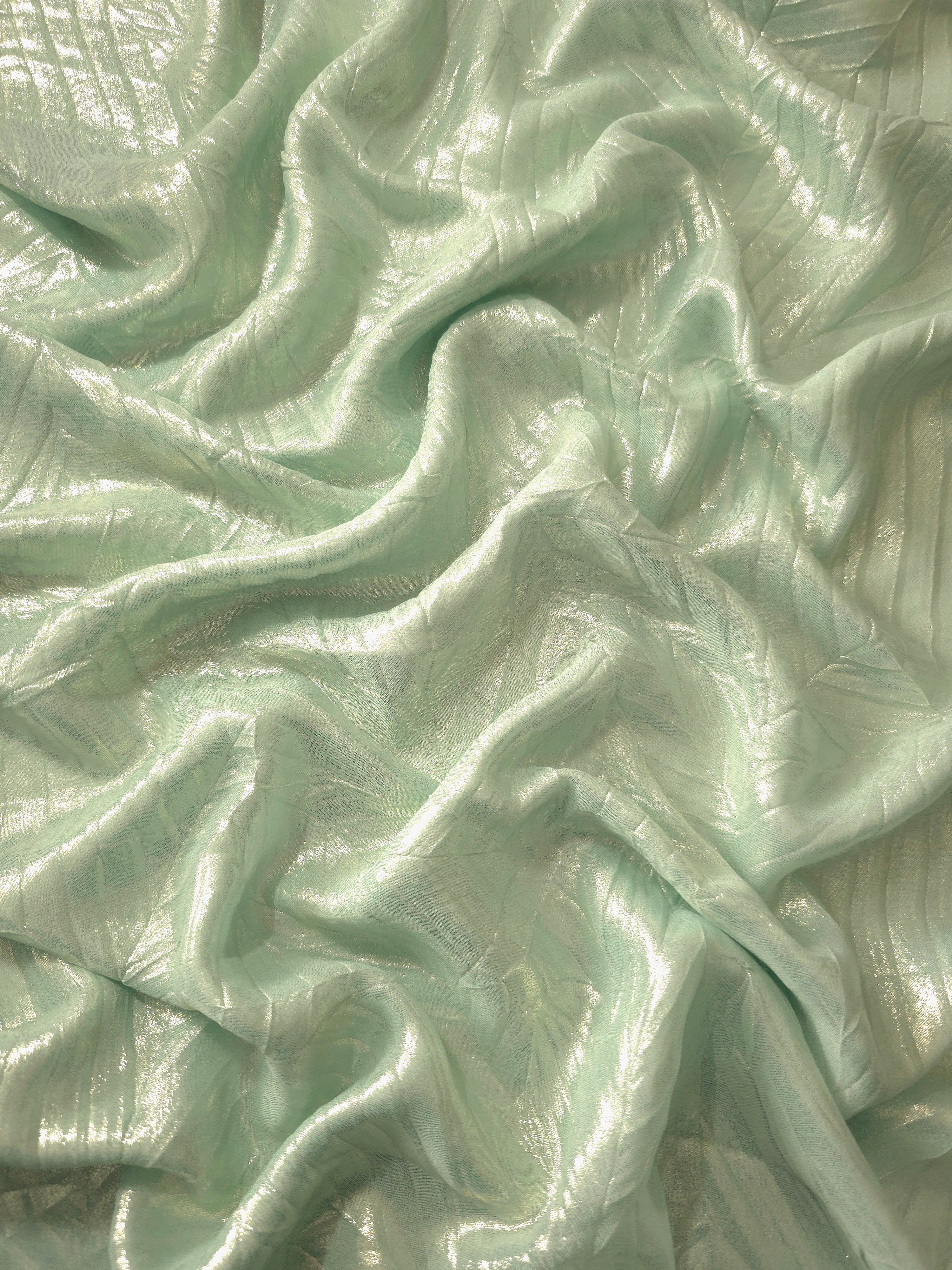 Flowing drape of Pale Sage leaf-pattern plissé shimmer fabric, showing sculpted leaf-like pleats and light-catching movement for evening gowns and flowing maxi skirts.