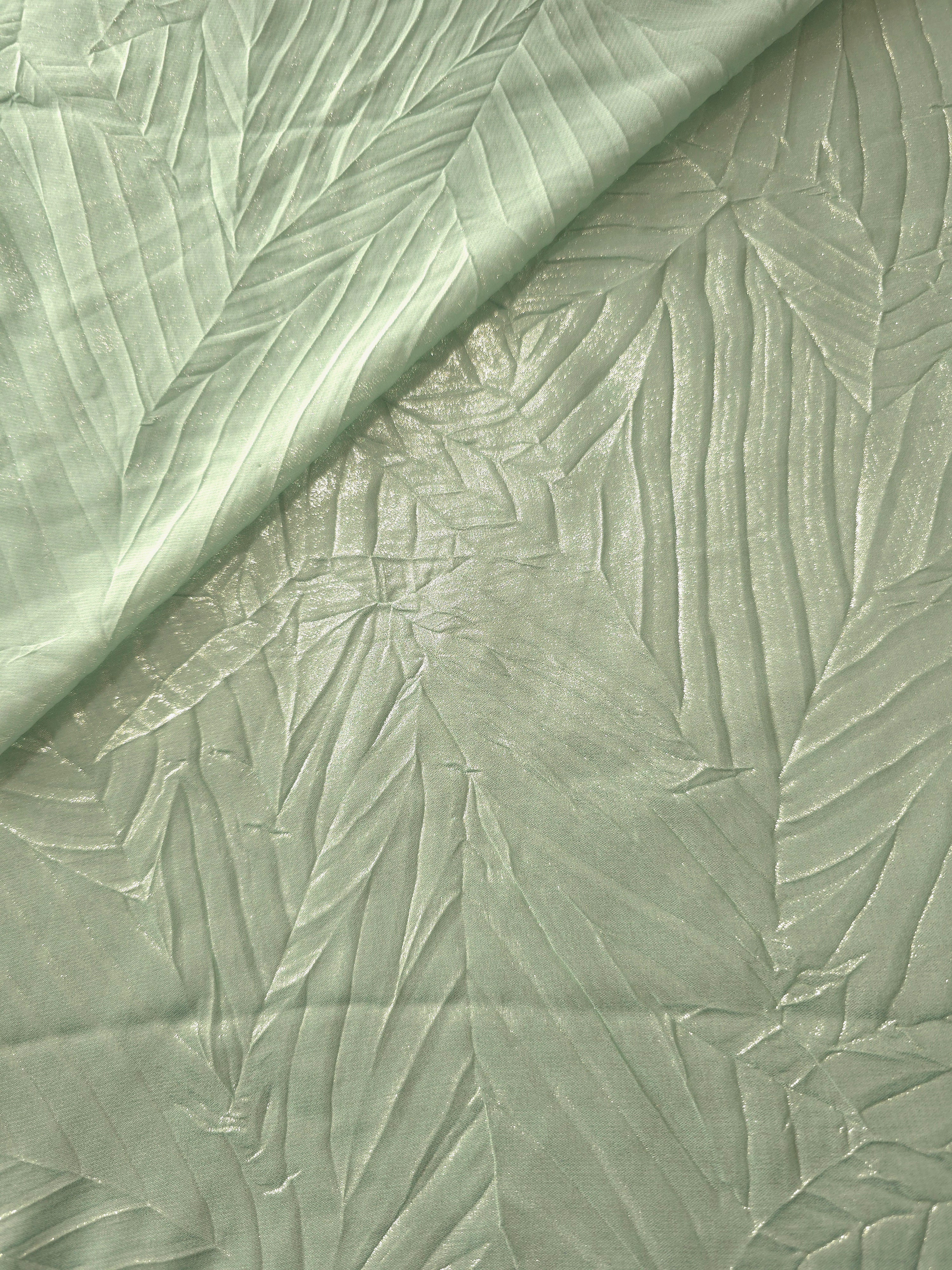 Fold detail of Pale Sage leaf-pattern plissé fabric demonstrates how the textured surface builds depth for stagewear and layered fashion details.