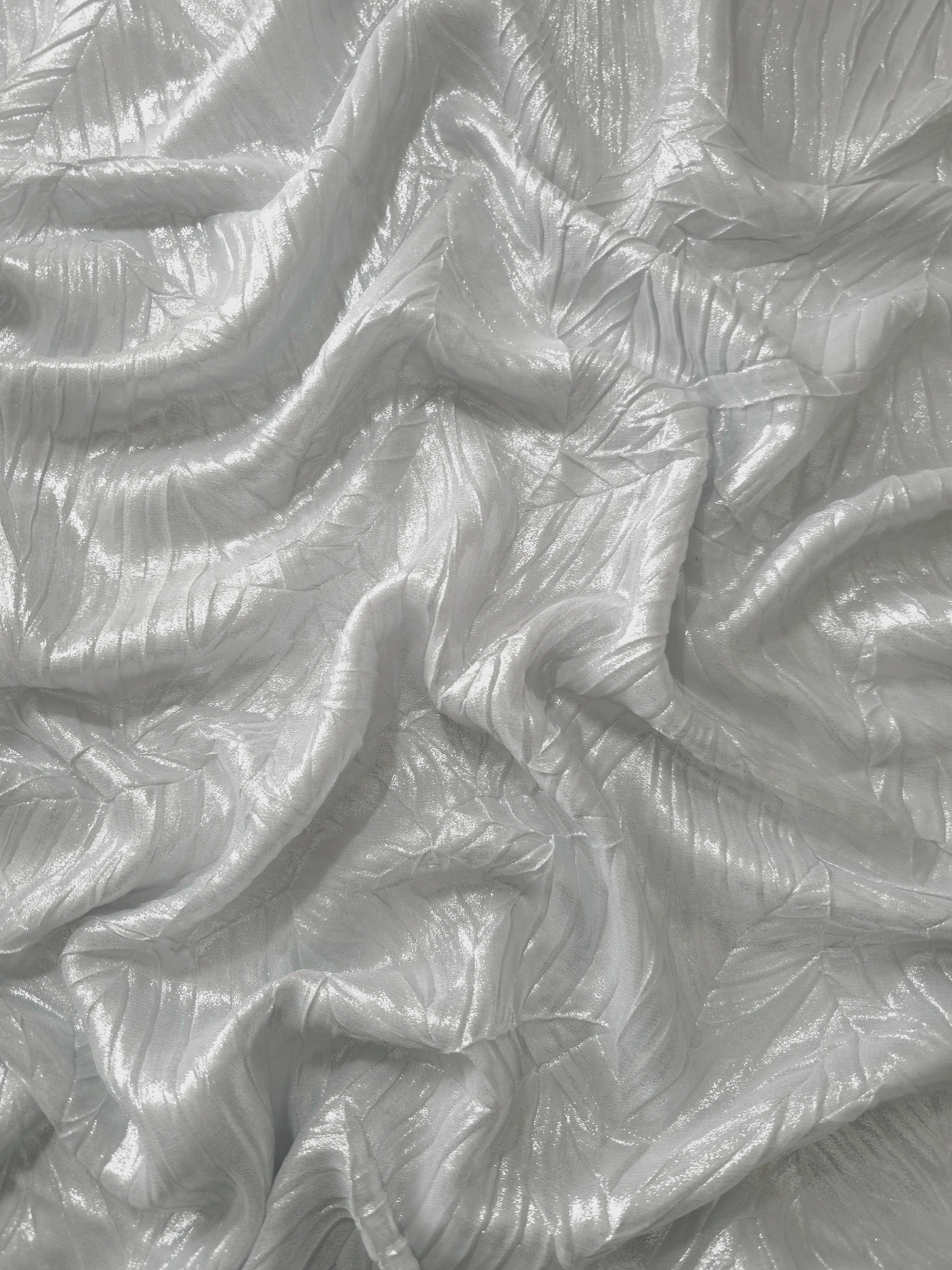 Flowing drape of Pearl Silver leaf-pattern plissé shimmer fabric, showing sculpted leaf-like pleats and light-catching movement for evening gowns and flowing maxi skirts.