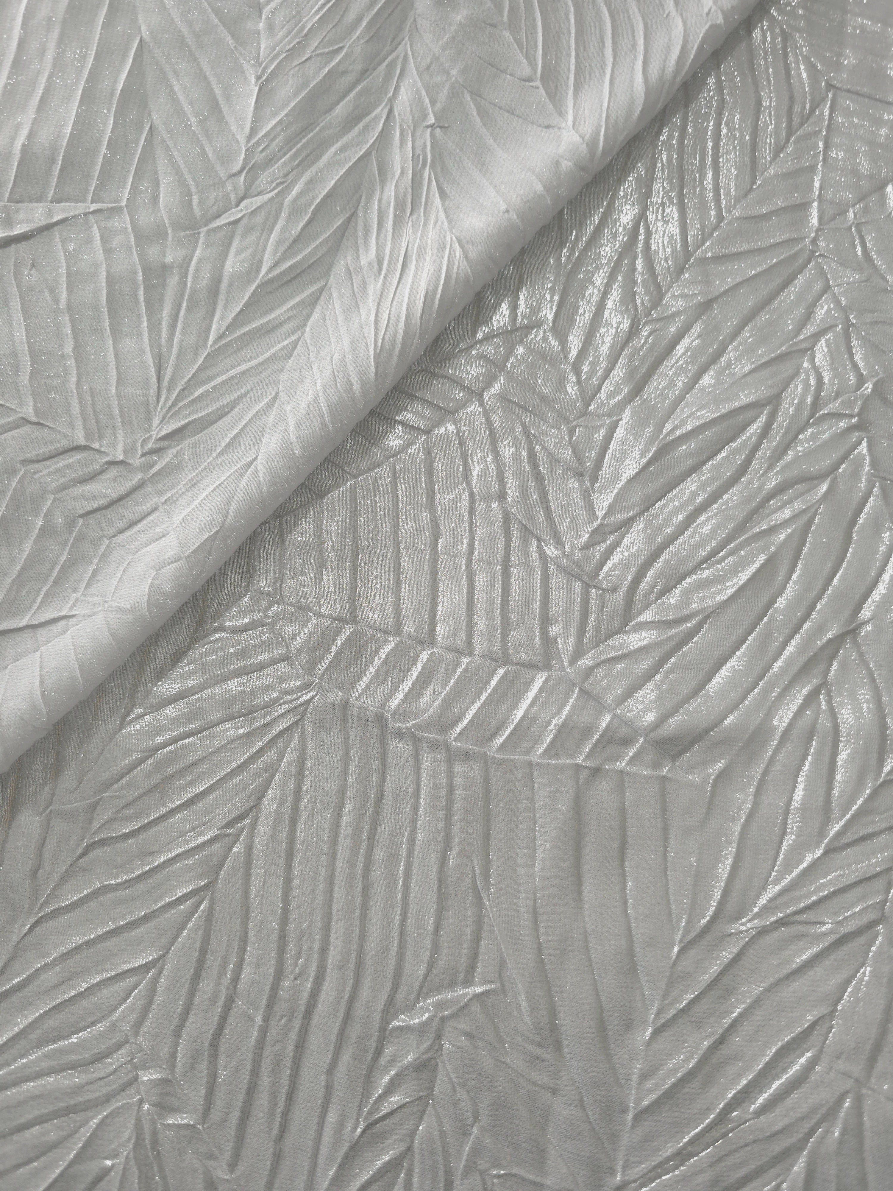 Fold detail of Pearl Silver leaf-pattern plissé fabric demonstrates how the textured surface builds depth for stagewear and layered fashion details.