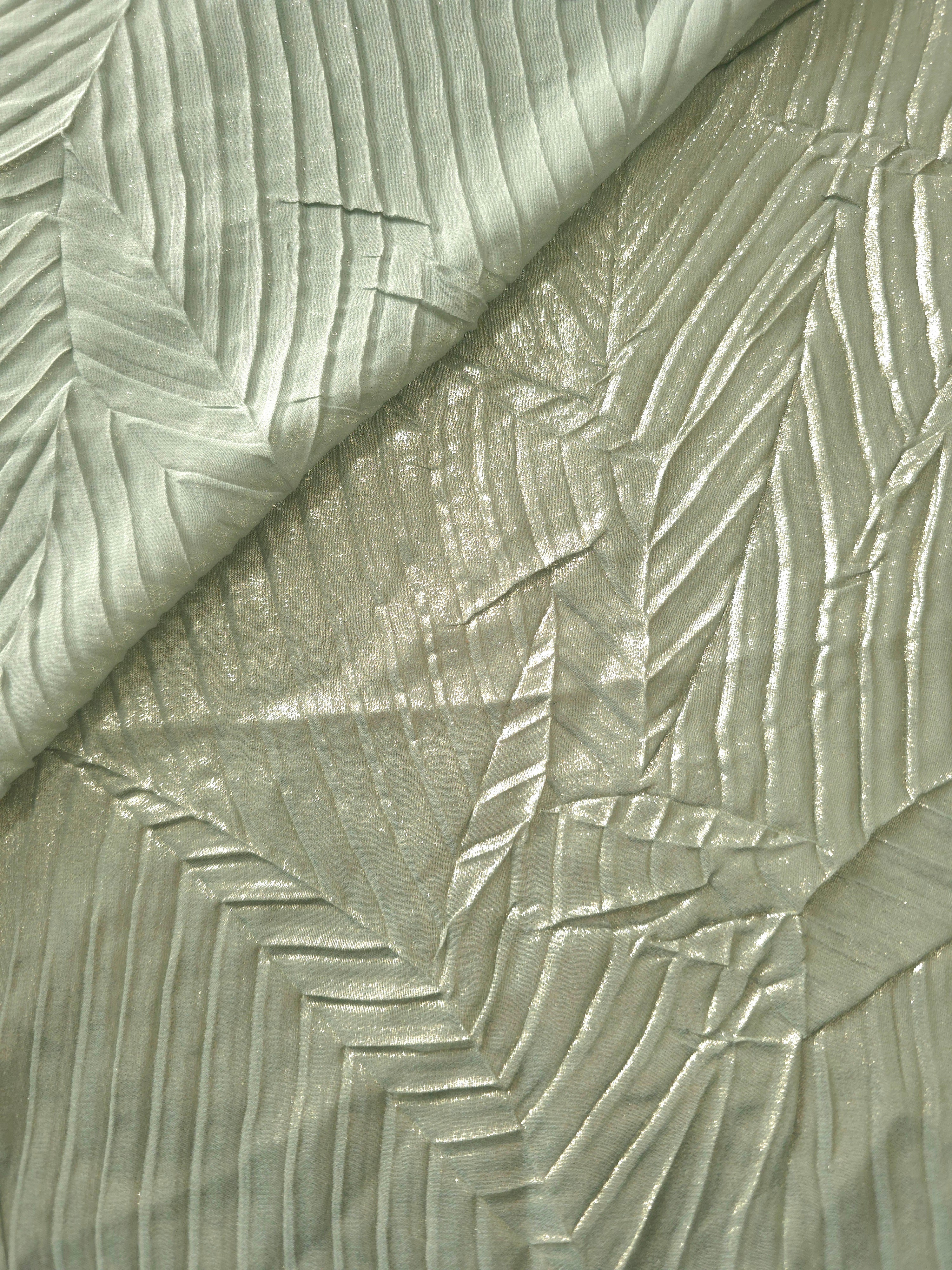 Fold detail of Sage Gray leaf-pattern plissé fabric demonstrates how the textured surface builds depth for stagewear and layered fashion details.