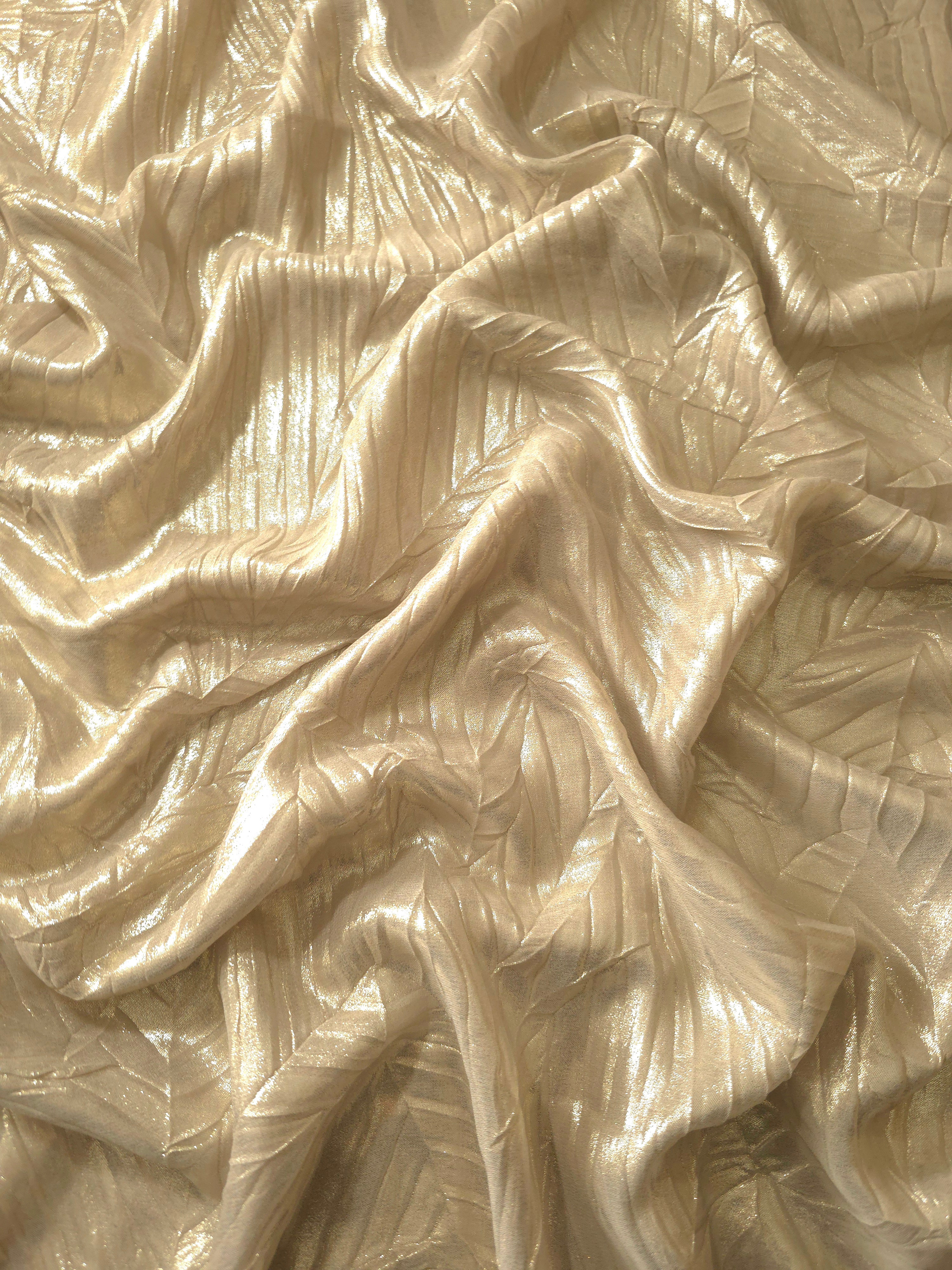 Flowing drape of Soft Champagne leaf-pattern plissé shimmer fabric, showing sculpted leaf-like pleats and light-catching movement for evening gowns and flowing maxi skirts.