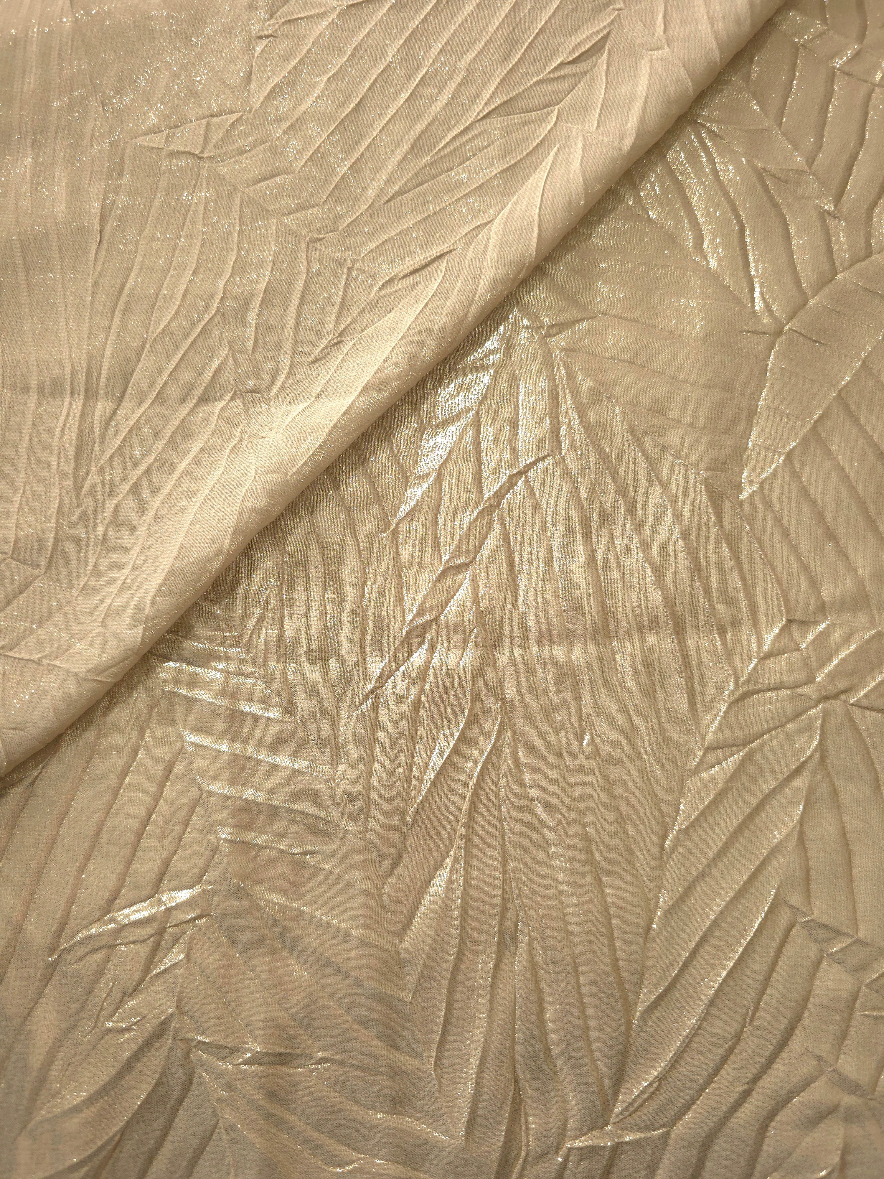 Fold detail of Soft Champagne leaf-pattern plissé fabric demonstrates how the textured surface builds depth for stagewear and layered fashion details.