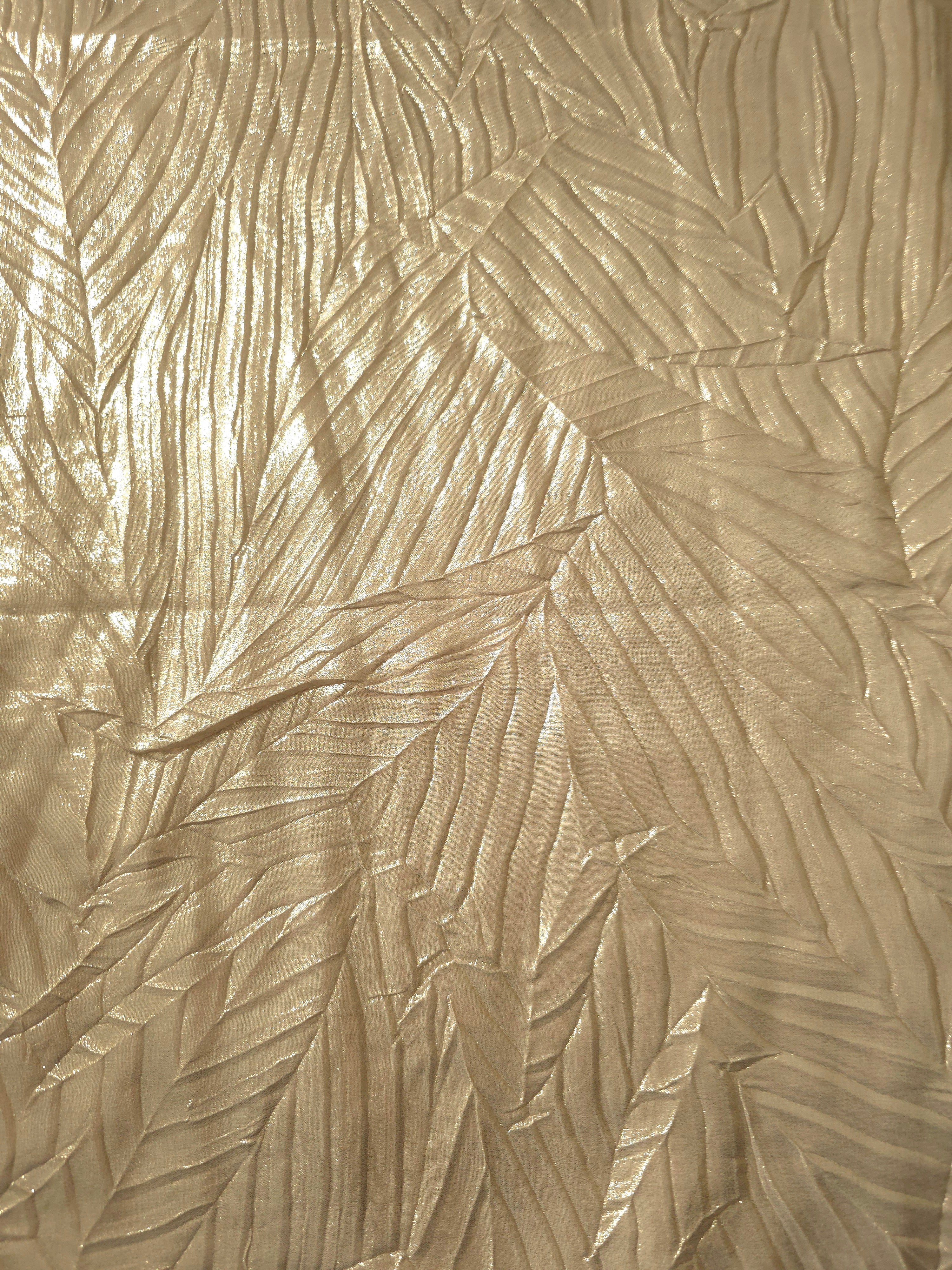 Surface detail of Soft Champagne leaf-pattern plissé shimmer fabric showcases sculpted leaf-like pleats for evening clutches, garment accents and special-occasion pieces.