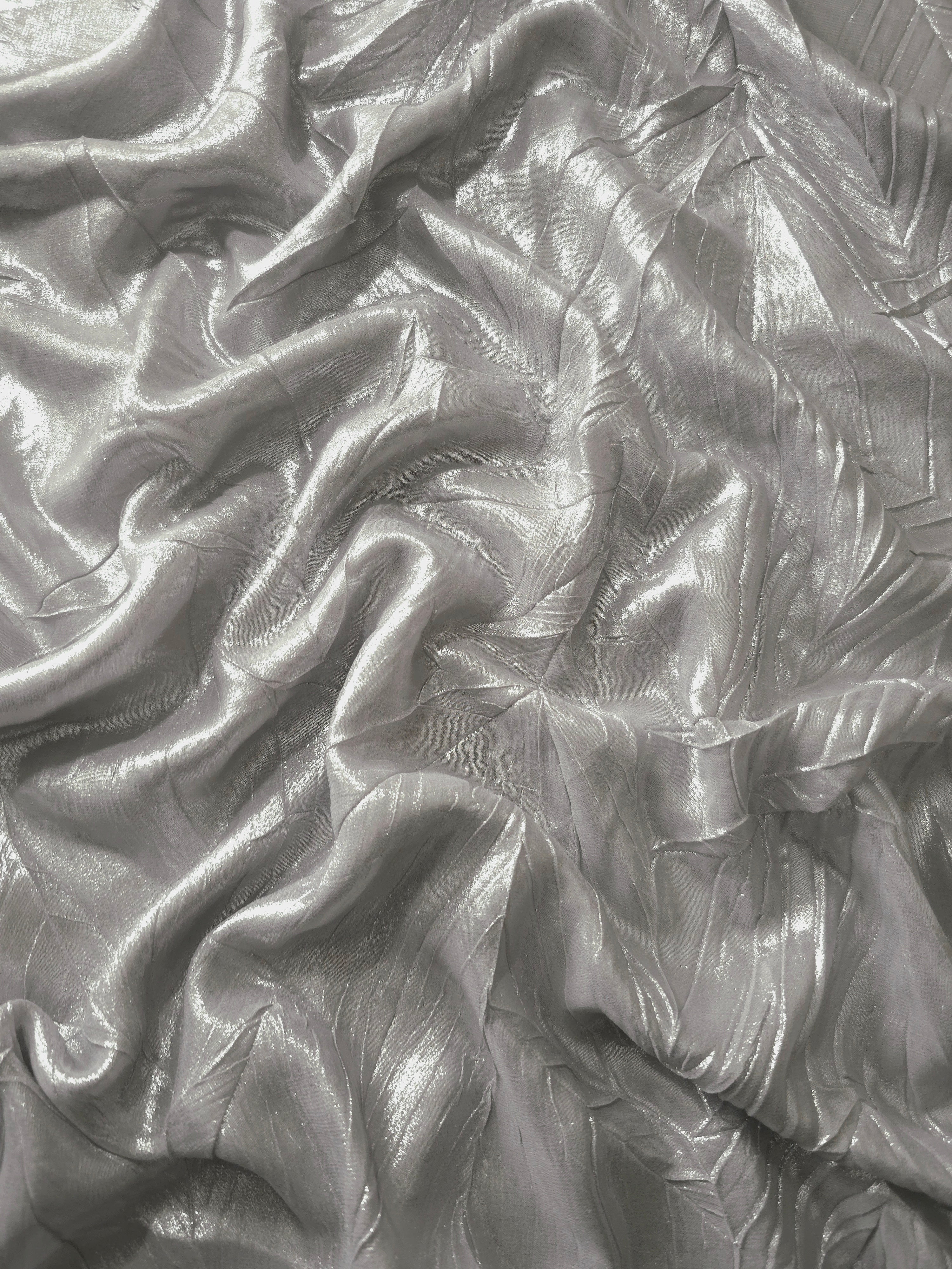 Flowing drape of Steel Silver leaf-pattern plissé shimmer fabric, showing sculpted leaf-like pleats and light-catching movement for evening gowns and flowing maxi skirts.