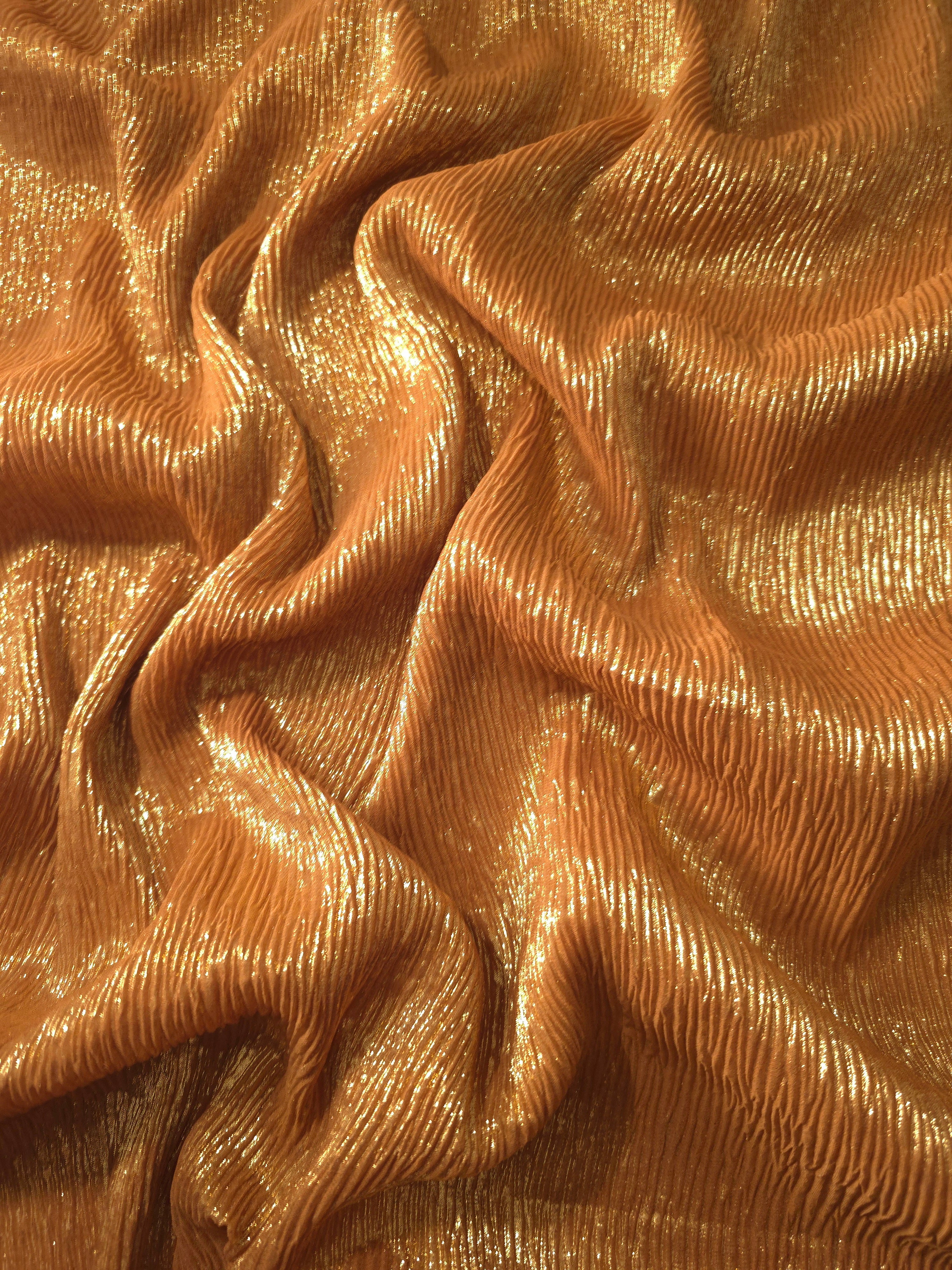 Flowing drape of Burnished Copper fine mini-plissé shimmer fabric, showing narrow micro-pleated texture and light-catching movement for evening gowns and flowing maxi skirts.