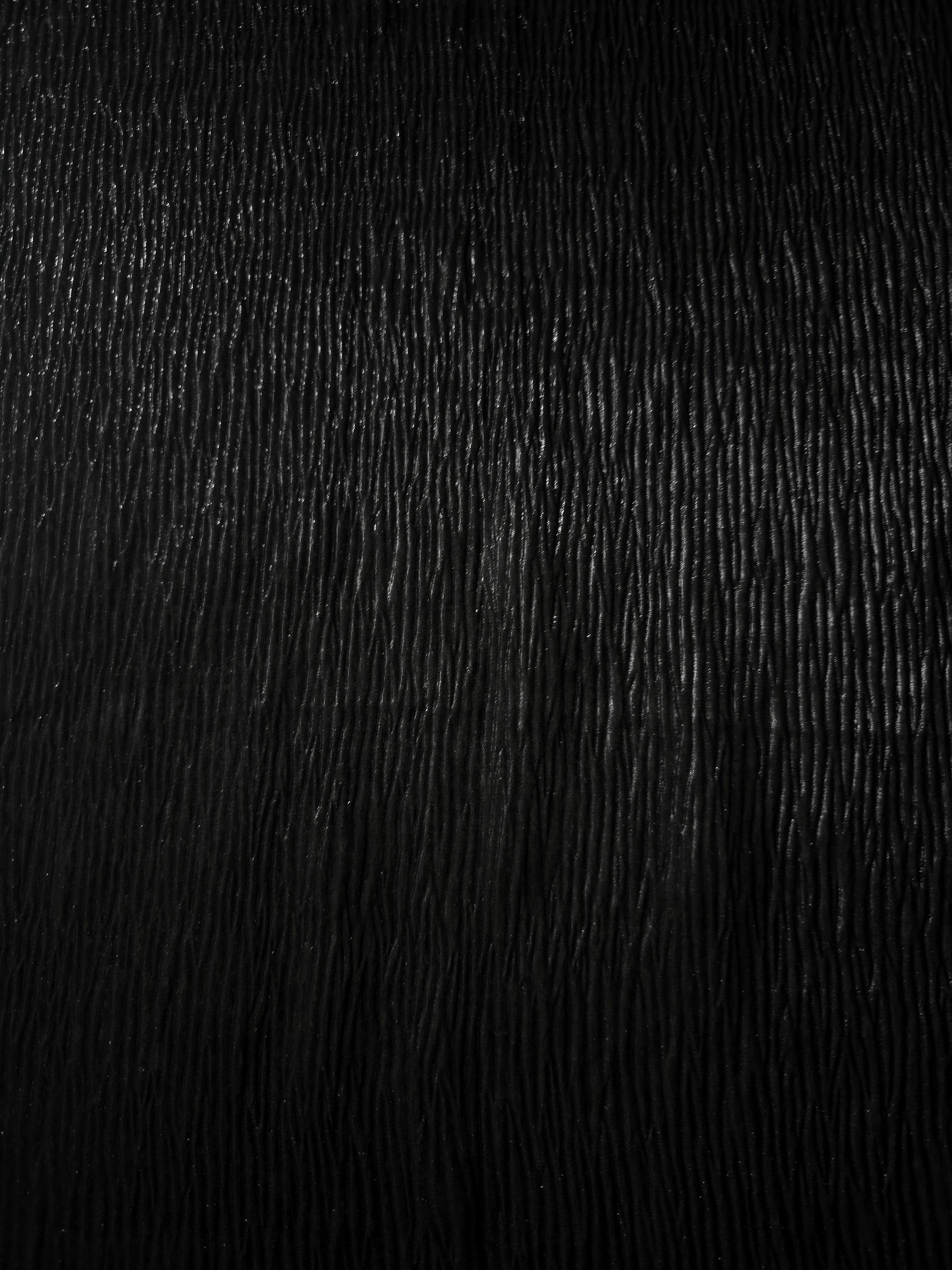 Surface detail of Jet Black fine mini-plissé shimmer fabric showcases narrow micro-pleated texture for evening clutches, garment accents and special-occasion pieces.