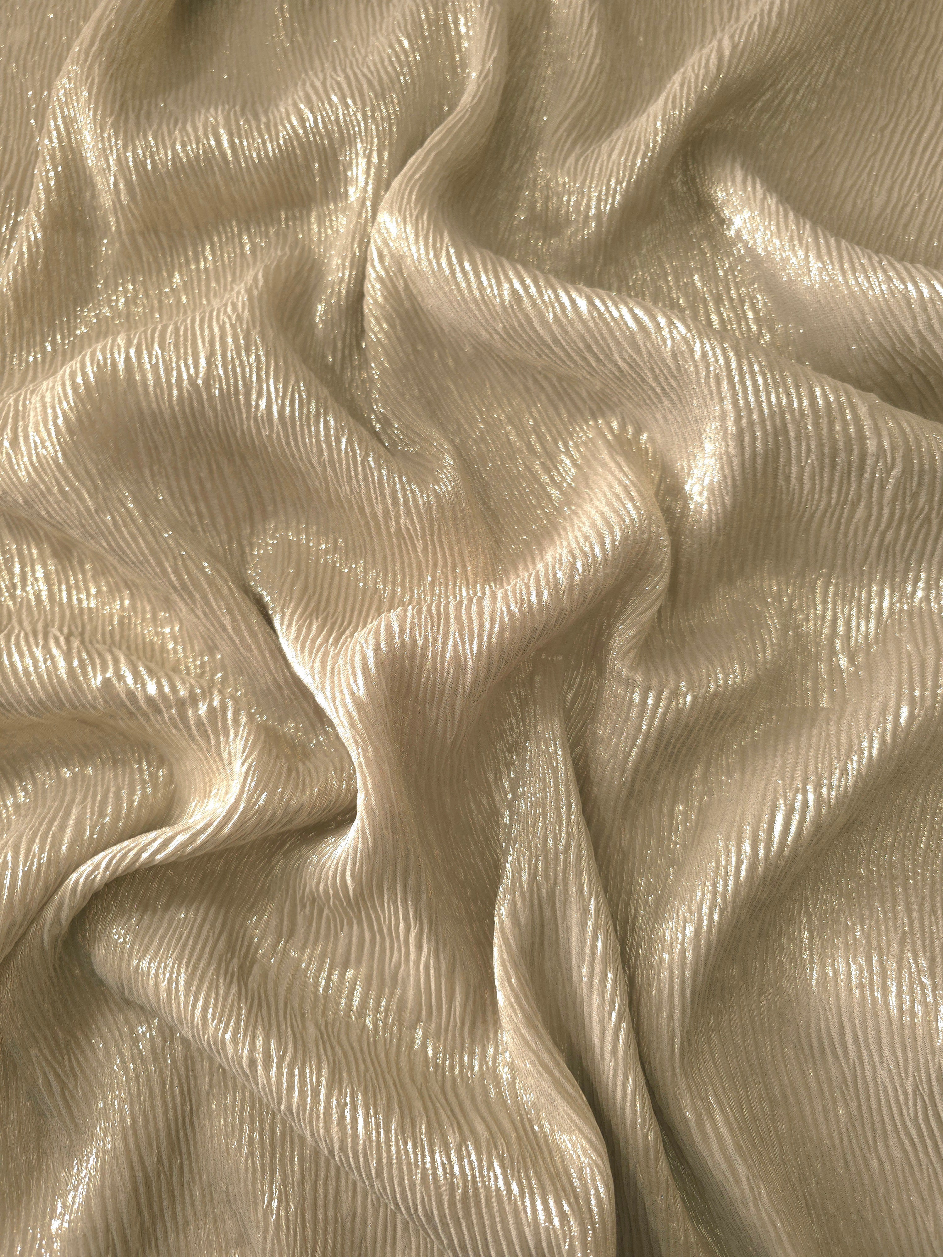 Flowing drape of Soft Champagne fine mini-plissé shimmer fabric, showing narrow micro-pleated texture and light-catching movement for evening gowns and flowing maxi skirts.