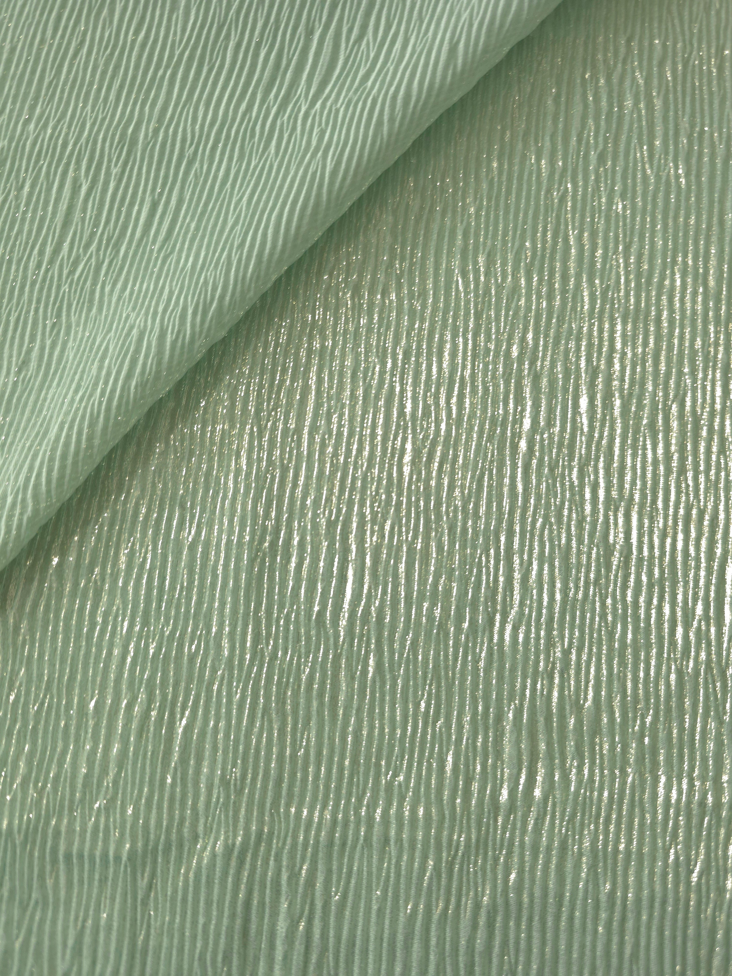 Fold detail of Soft Sage fine mini-plissé fabric demonstrates how the textured surface builds depth for stagewear and layered fashion details.
