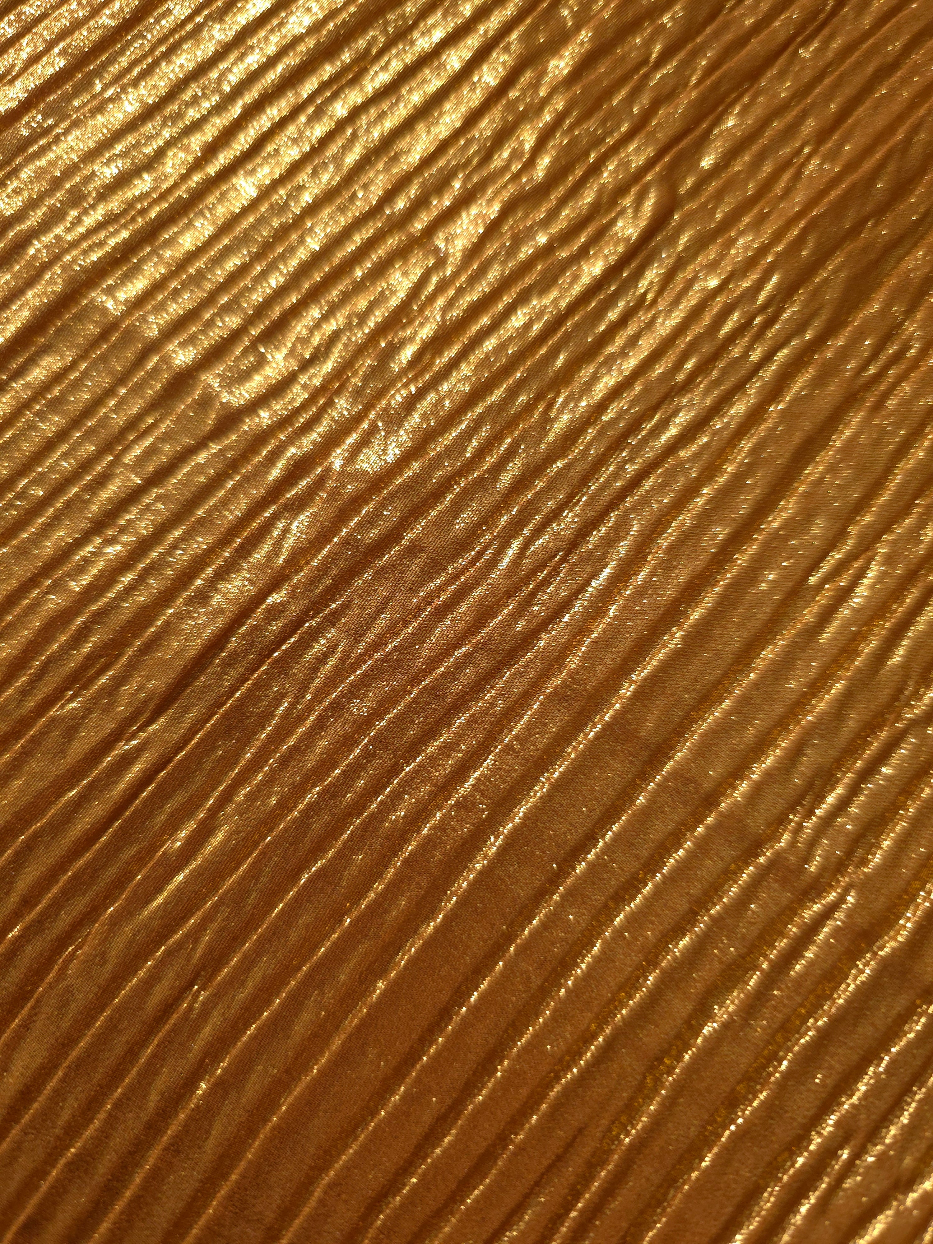 Soft drape of Amber Gold textured shimmer plissé reveals dimensional folds and shifting reflection for jumpsuits and fluid occasionwear.