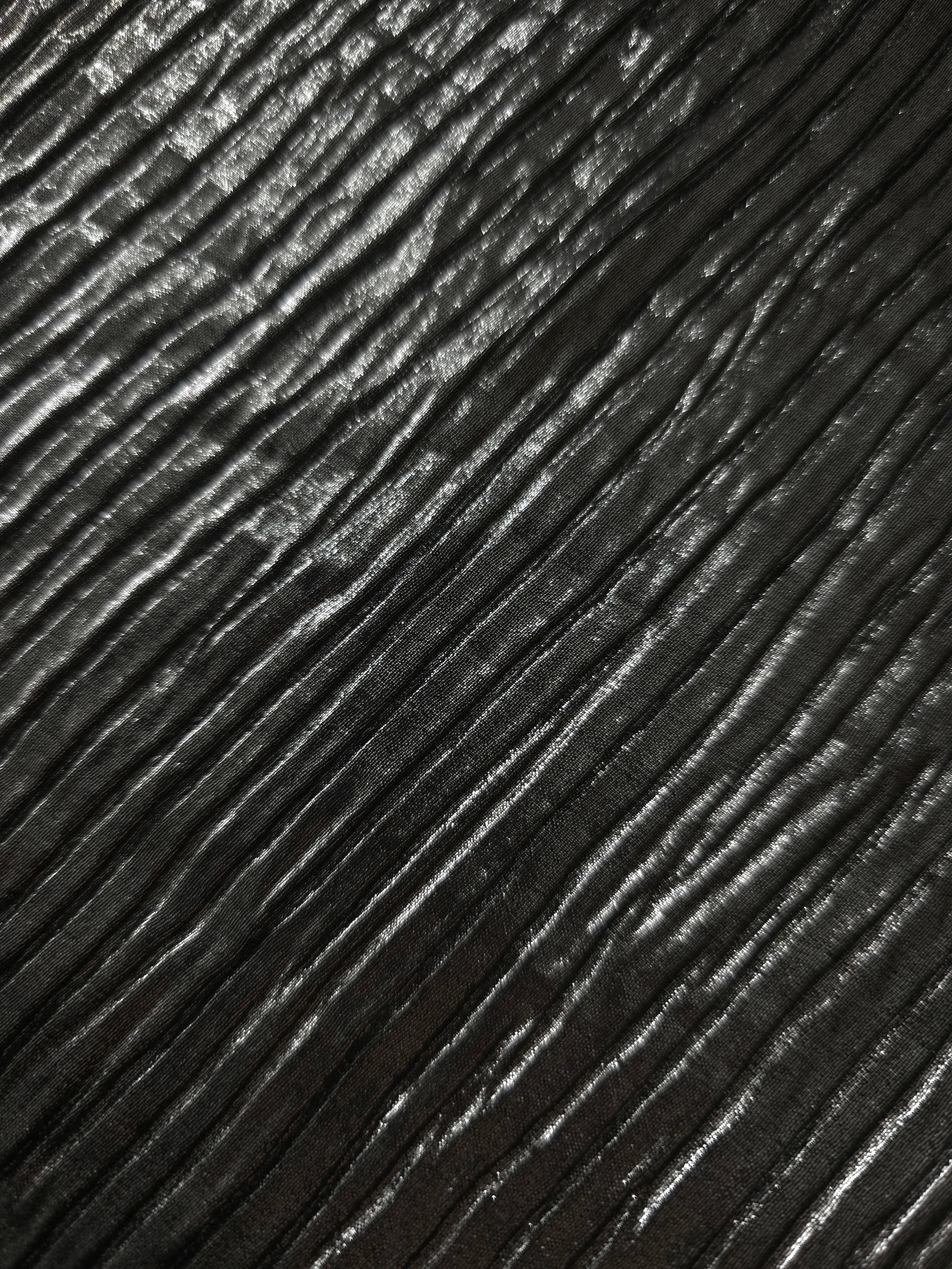 Soft drape of Charcoal Black textured shimmer plissé reveals dimensional folds and shifting reflection for jumpsuits and fluid occasionwear.