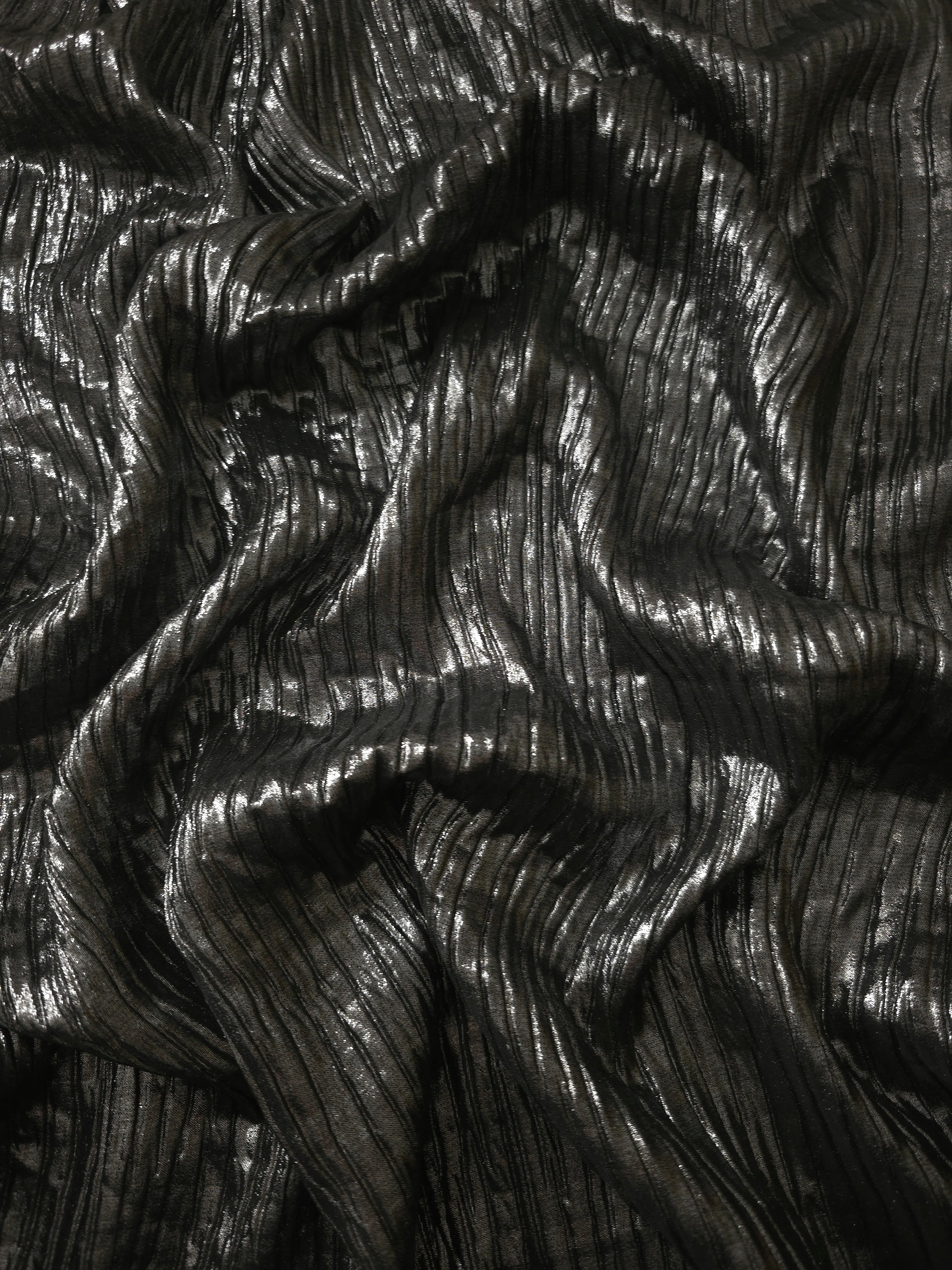 Flowing drape of Charcoal Black classic plissé shimmer fabric, showing regular pleated texture and light-catching movement for evening gowns and flowing maxi skirts.