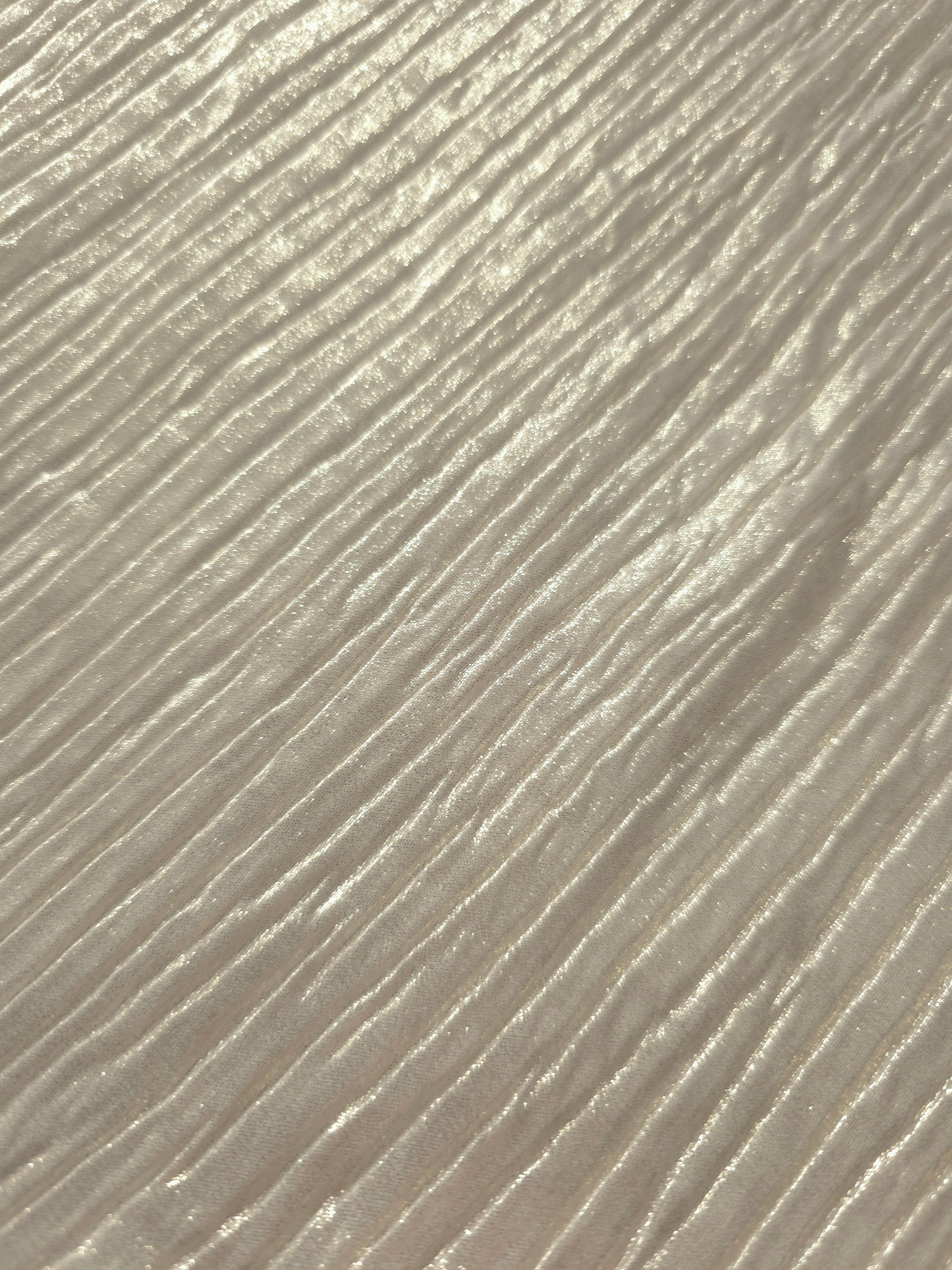 Soft drape of Ivory Cream textured shimmer plissé reveals dimensional folds and shifting reflection for jumpsuits and fluid occasionwear.