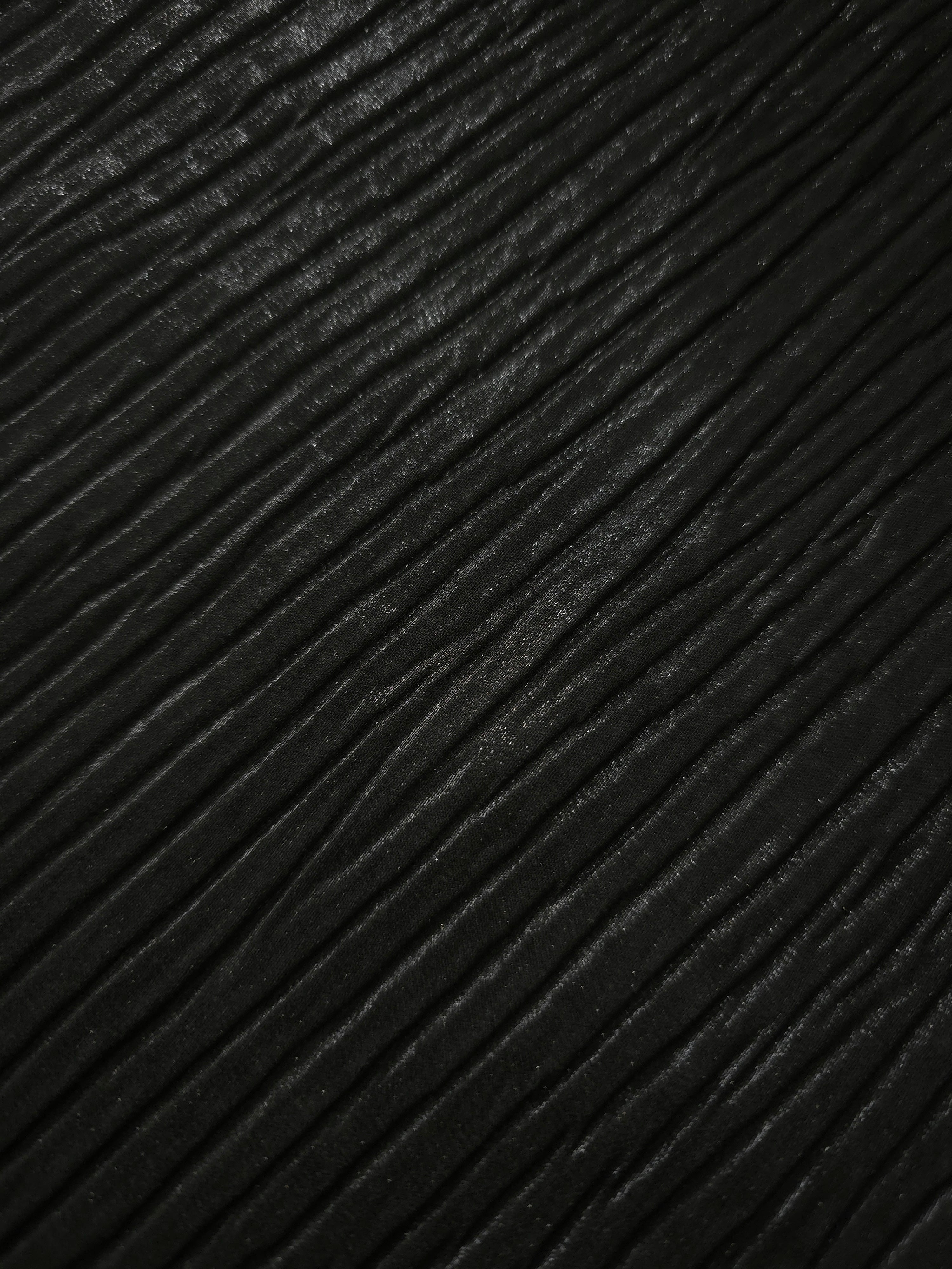 Soft drape of Jet Black textured shimmer plissé reveals dimensional folds and shifting reflection for jumpsuits and fluid occasionwear.