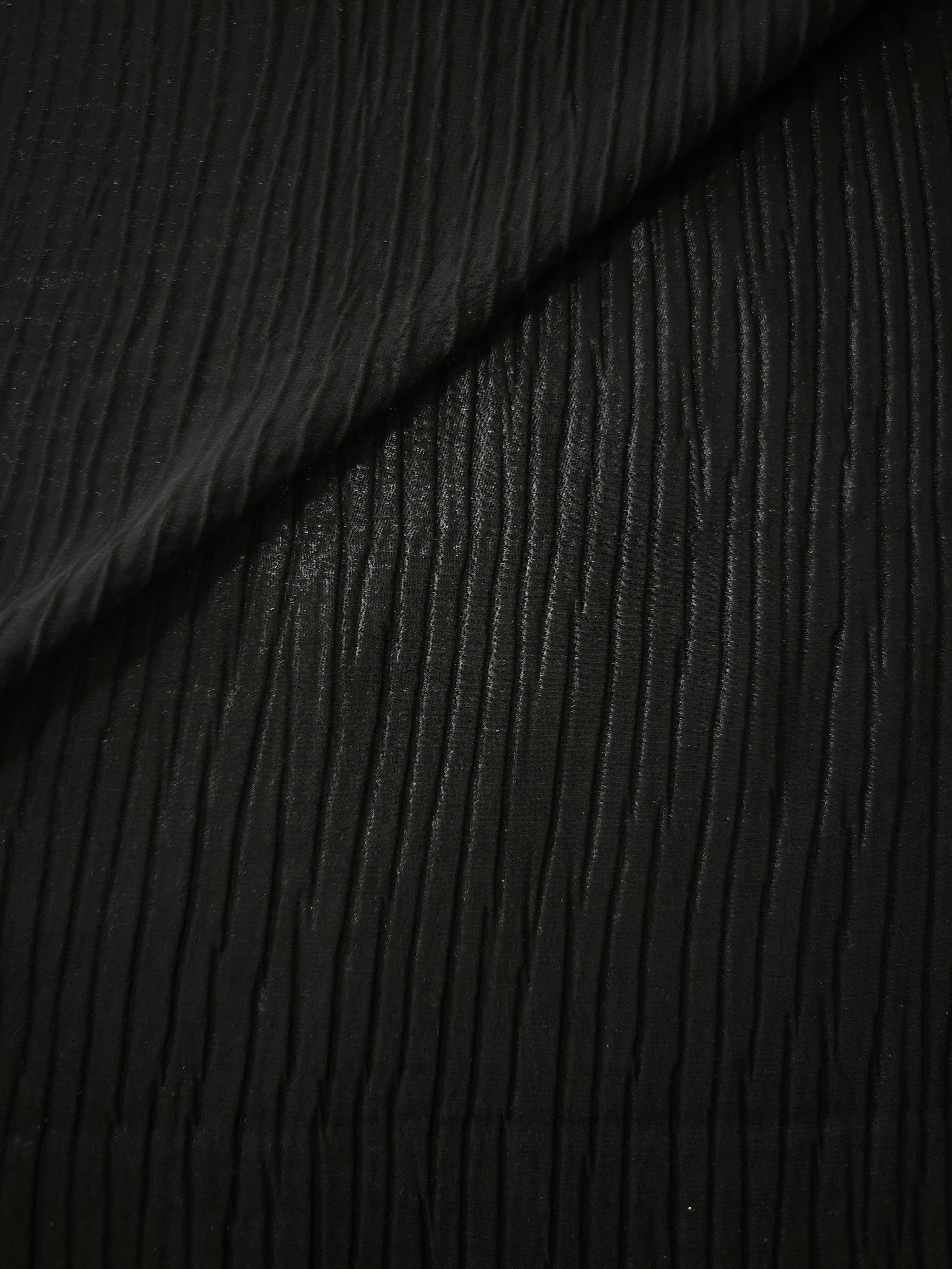 Fold detail of Jet Black classic plissé fabric demonstrates how the textured surface builds depth for stagewear and layered fashion details.